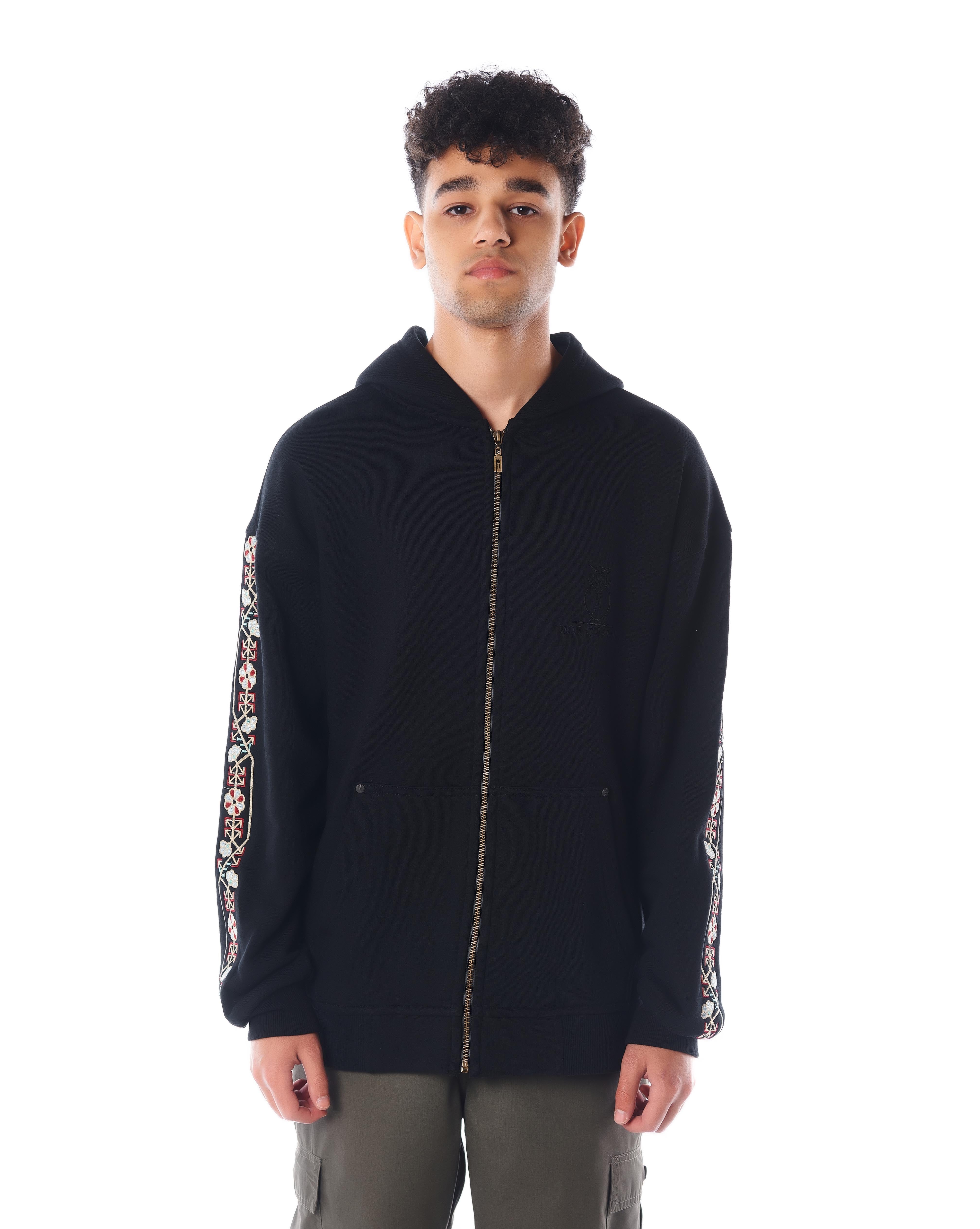 The Culture Zip-Hoodie von MOE CHARLIE, Frontaufnahme, Fokus auf Goldreißverschluss und florale Ärmelstickerei
