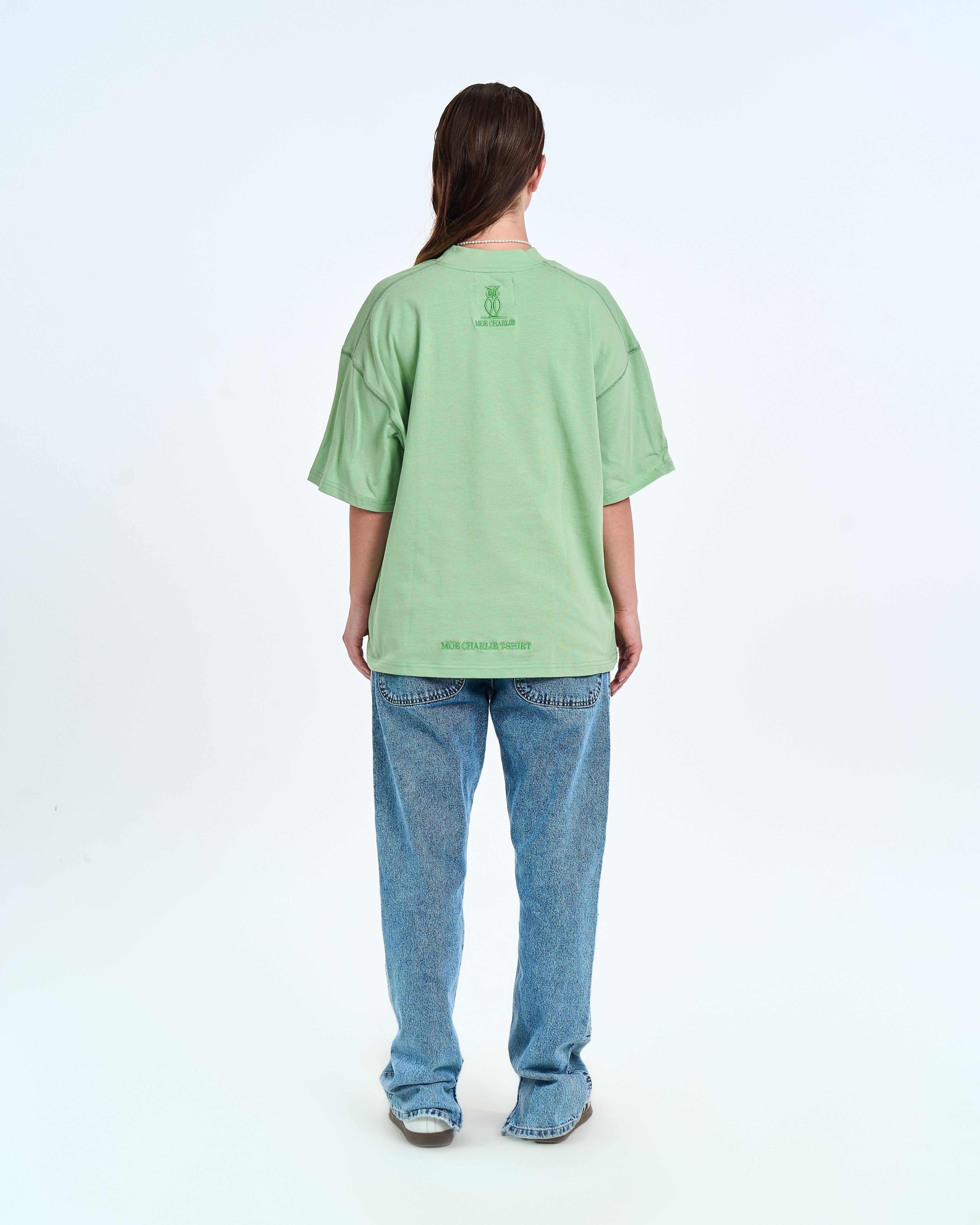 MOE CHARLIE Born In Exile T-Shirt Mintgrün – Rückenansicht Damenmodel, Eulen-Logo und Saum-Stickerei