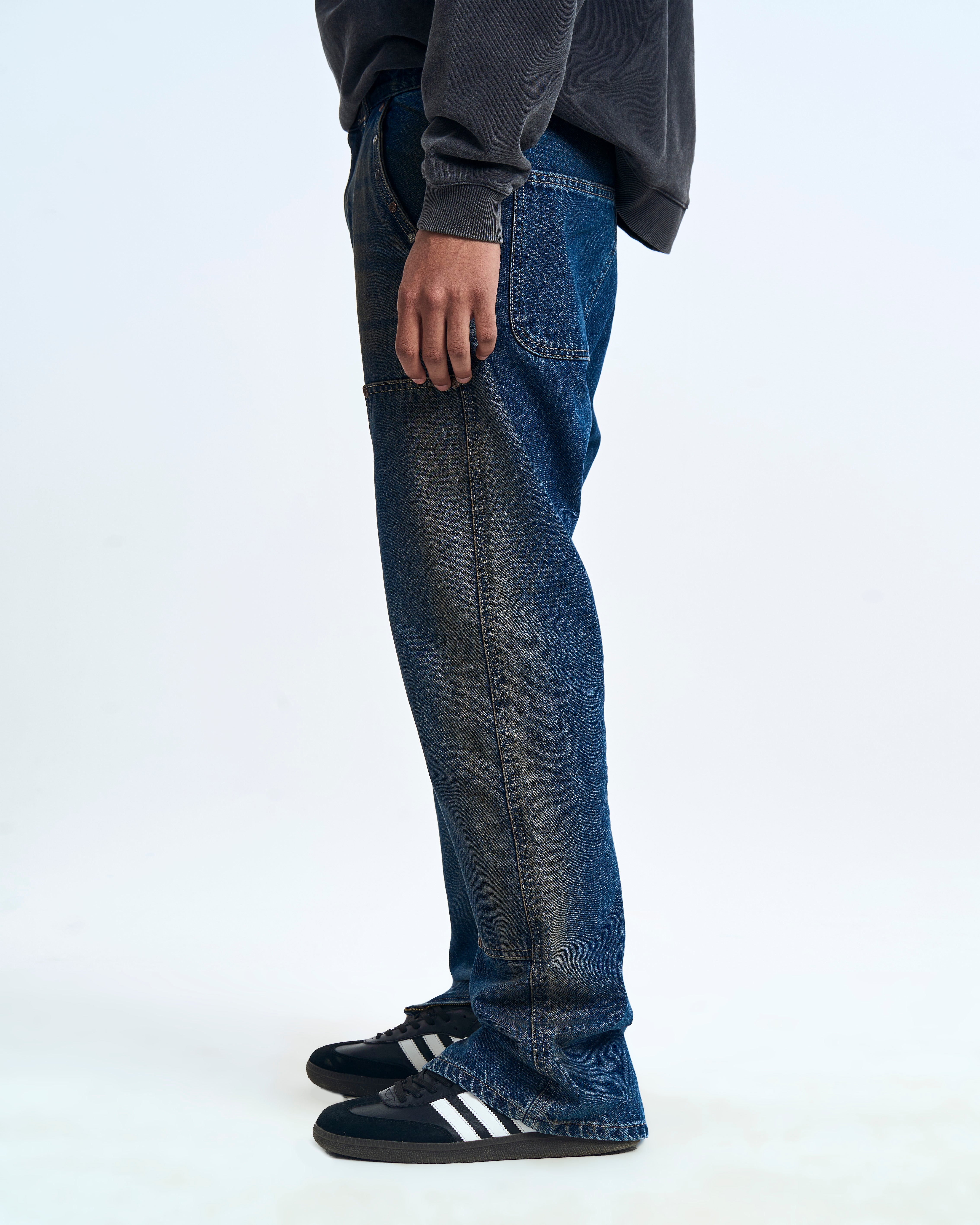 MOE CHARLIE Double Knee Flare Denim Seitenansicht links – dunkle Waschung, Worker-Paneele, Adidas Sneakers