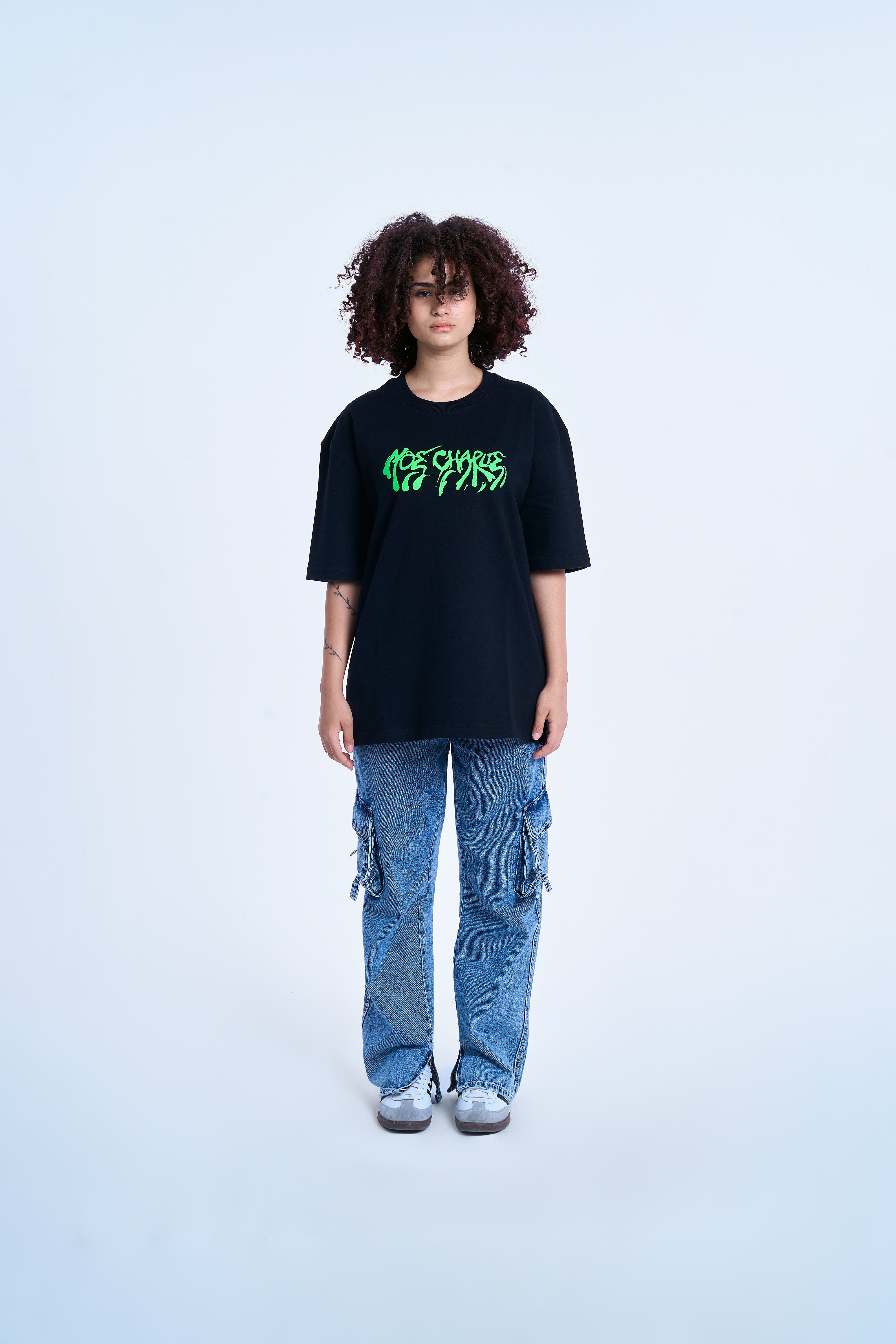 MOE CHARLIE Graffiti T-Shirt, Frontansicht weiblich, grüner Print, Oversize-Look mit Cargo-Jeans kombiniert