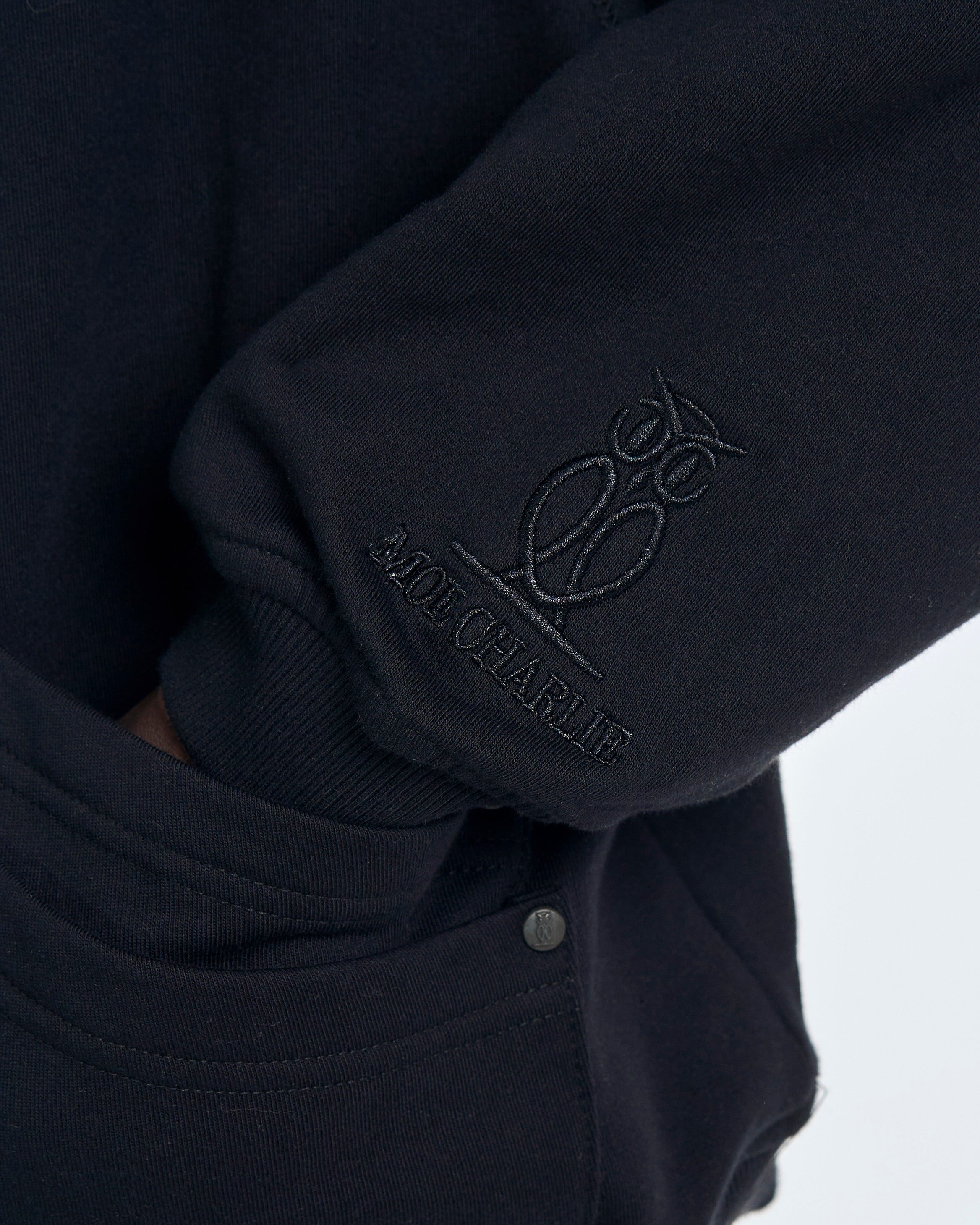 Detailaufnahme Ärmelstickerei MOE CHARLIE Cangaroo Hoodie – Logo und Schriftzug am Bündchen