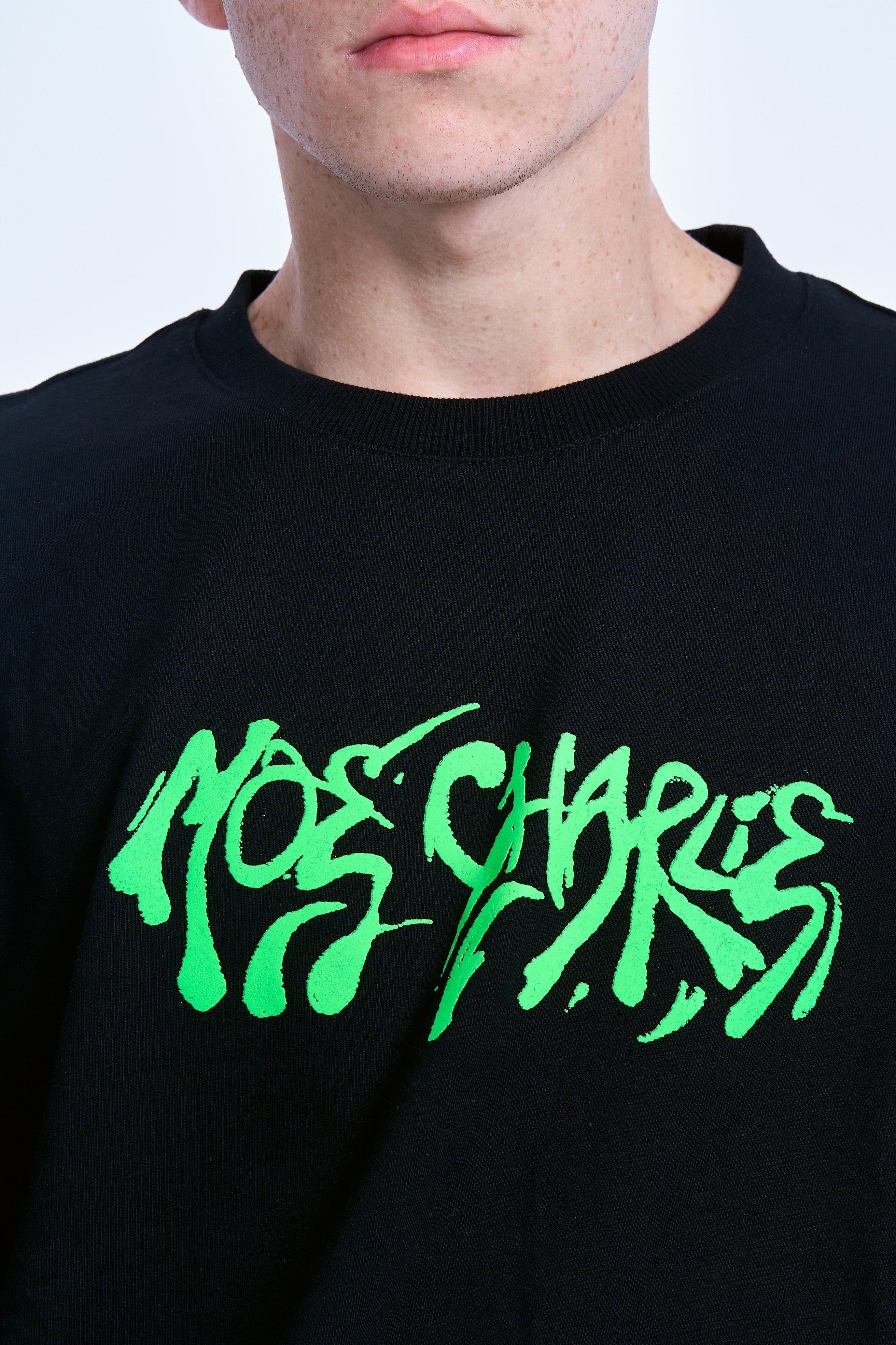 Detailaufnahme Graffiti-Print MOE CHARLIE – neon-grüner Street-Art-Schriftzug auf schwarzem Baumwollstoff