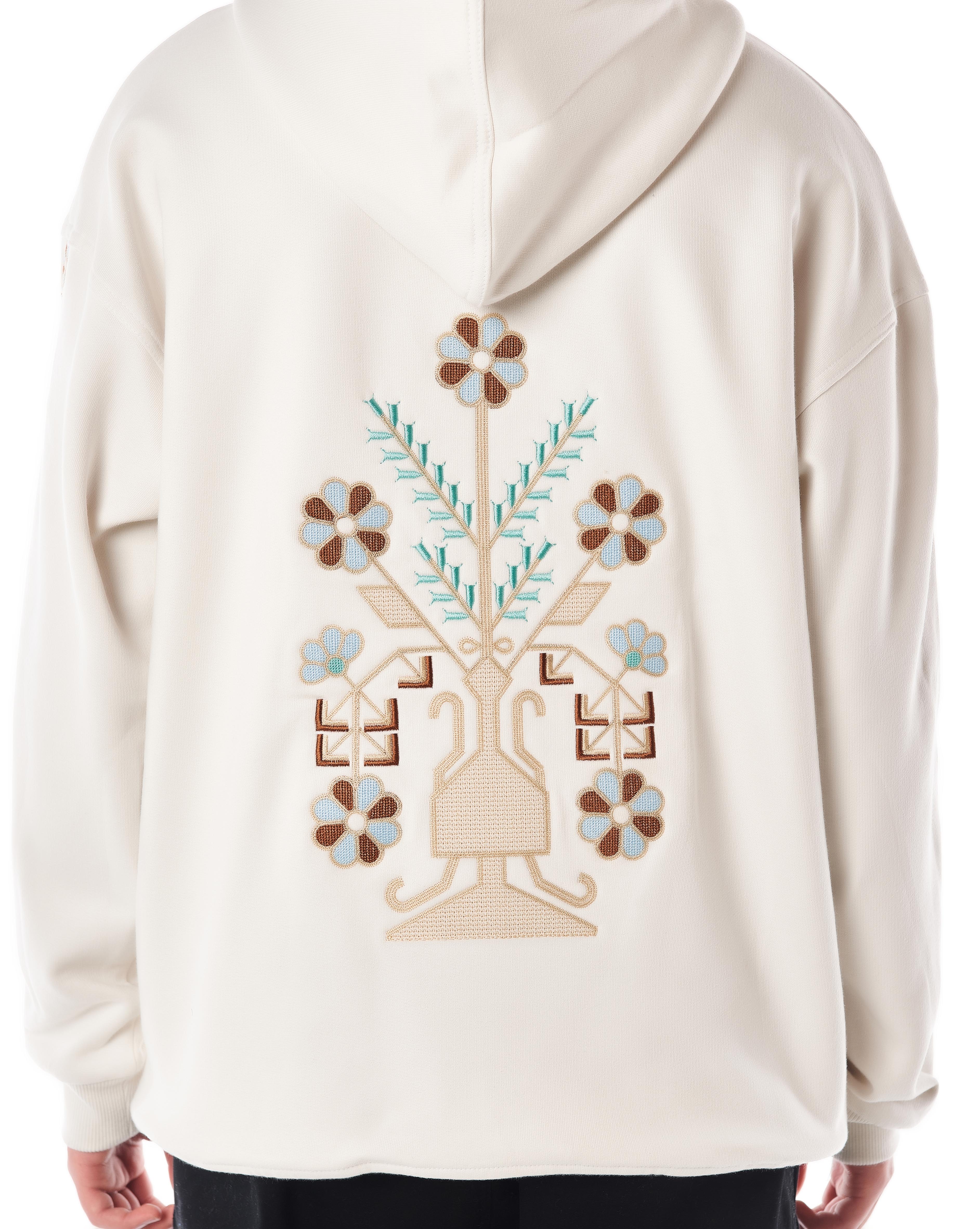 Nahaufnahme der großen Rücken-Stickerei des Star White Hoodies, florales Vasenmotiv in Braun, Beige und Türkis