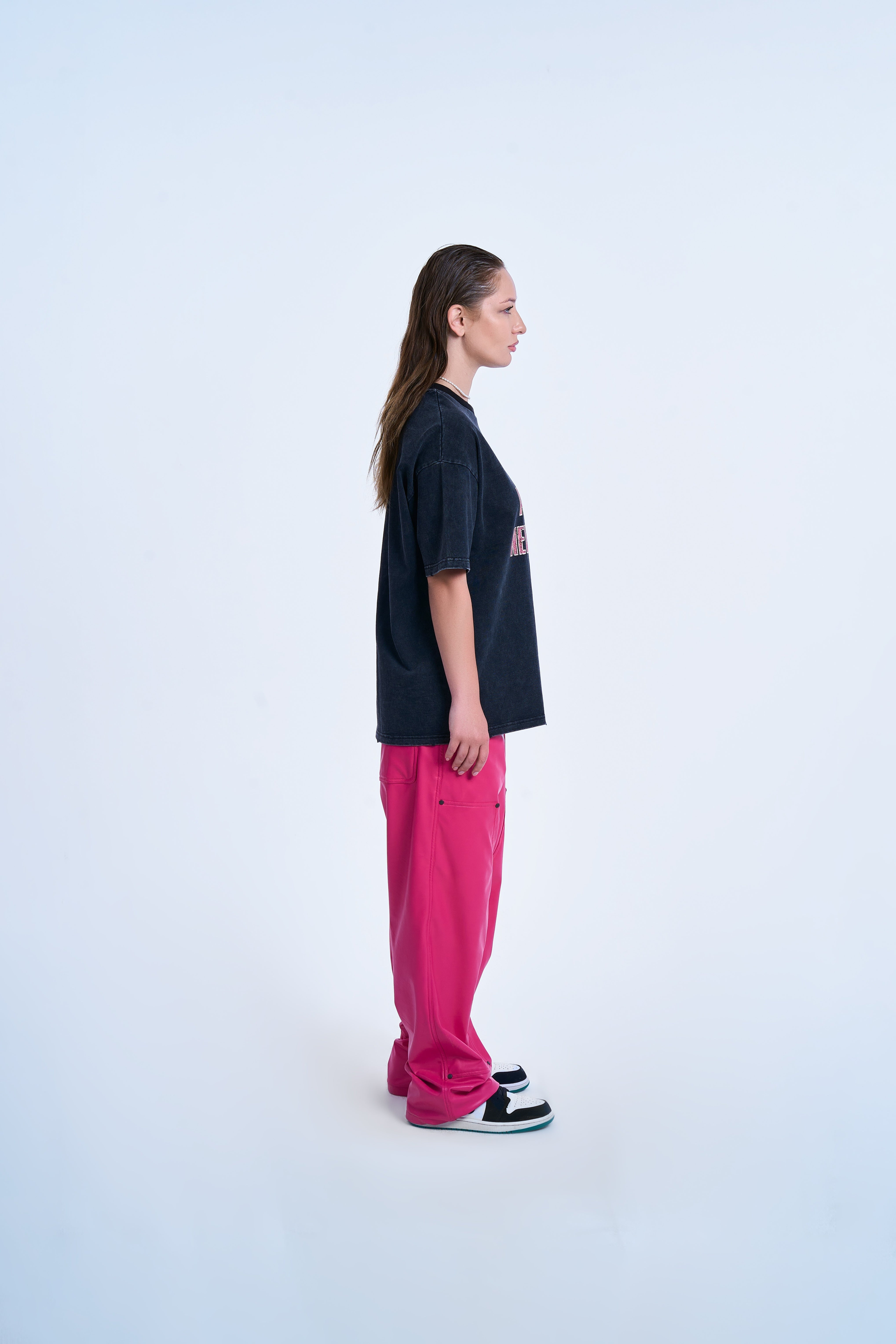 MOE CHARLIE Never Lonely T-Shirt – Seitenansicht rechts, Oversize-Länge, Hot-Pink-Lederhose und Jordan-Sneaker