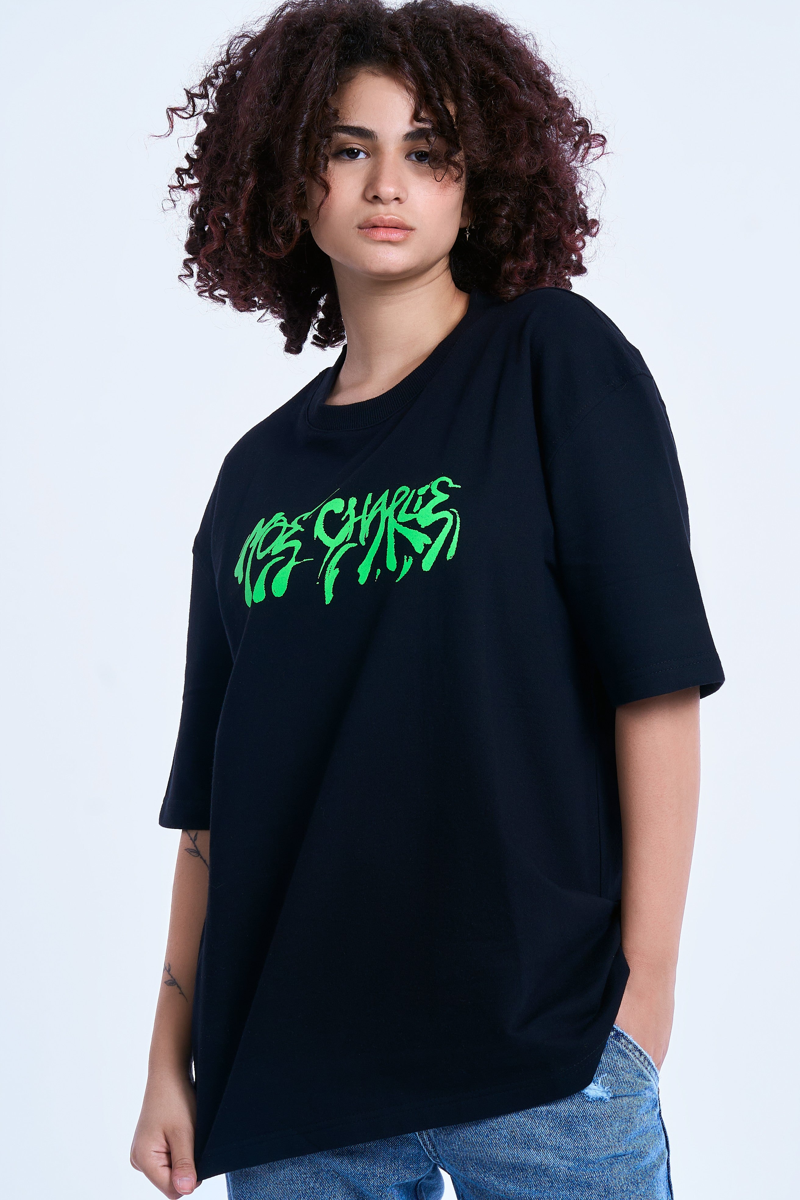 Graffiti T-Shirt MOE CHARLIE in Schwarz, Halbkörperaufnahme weiblich, neon-grüner Schriftzug seitlich