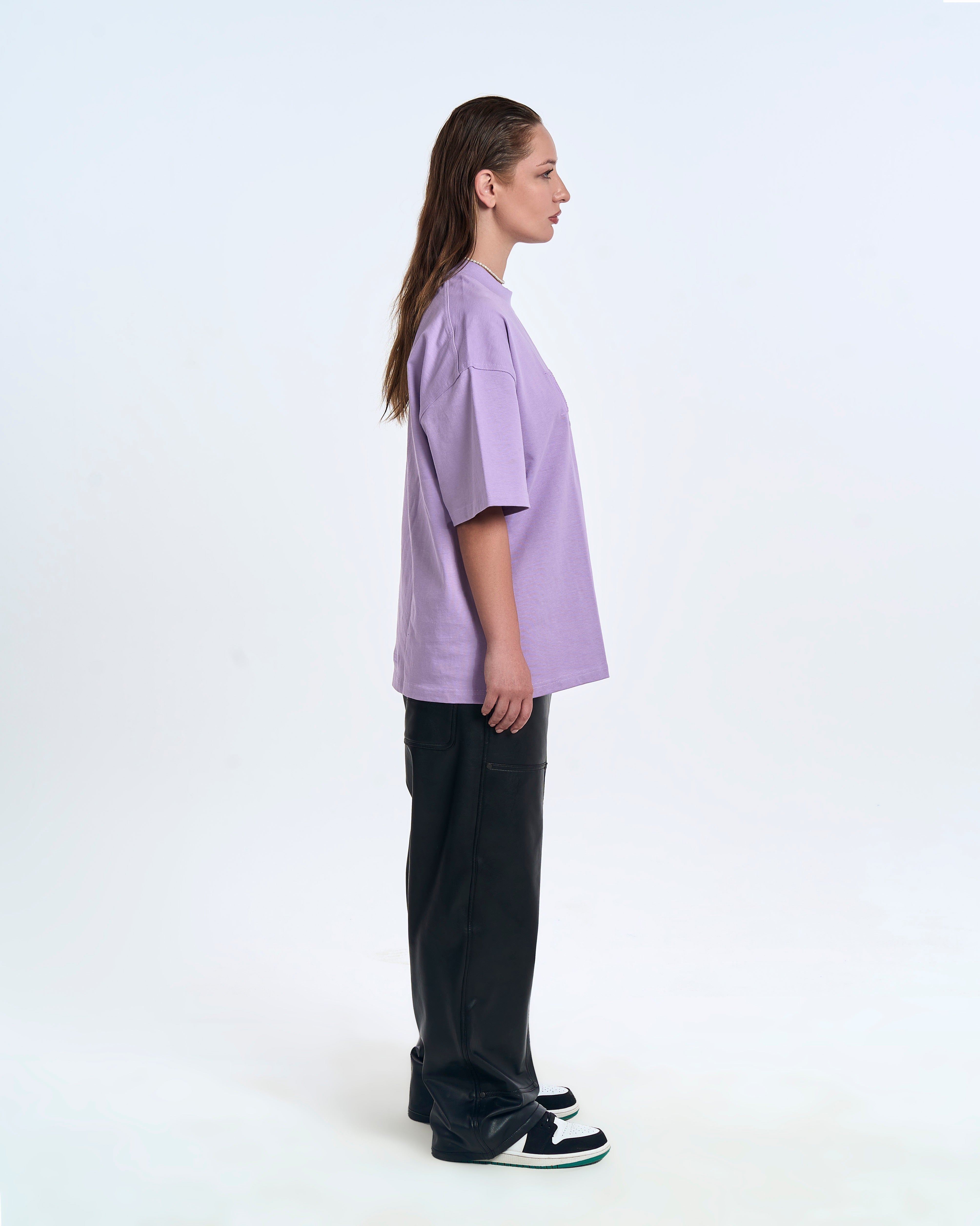 MOE CHARLIE Born In Exile T-Shirt Lavendel – Seitenansicht Damenmodel, Oversize-Länge, schwarze Lederhose
