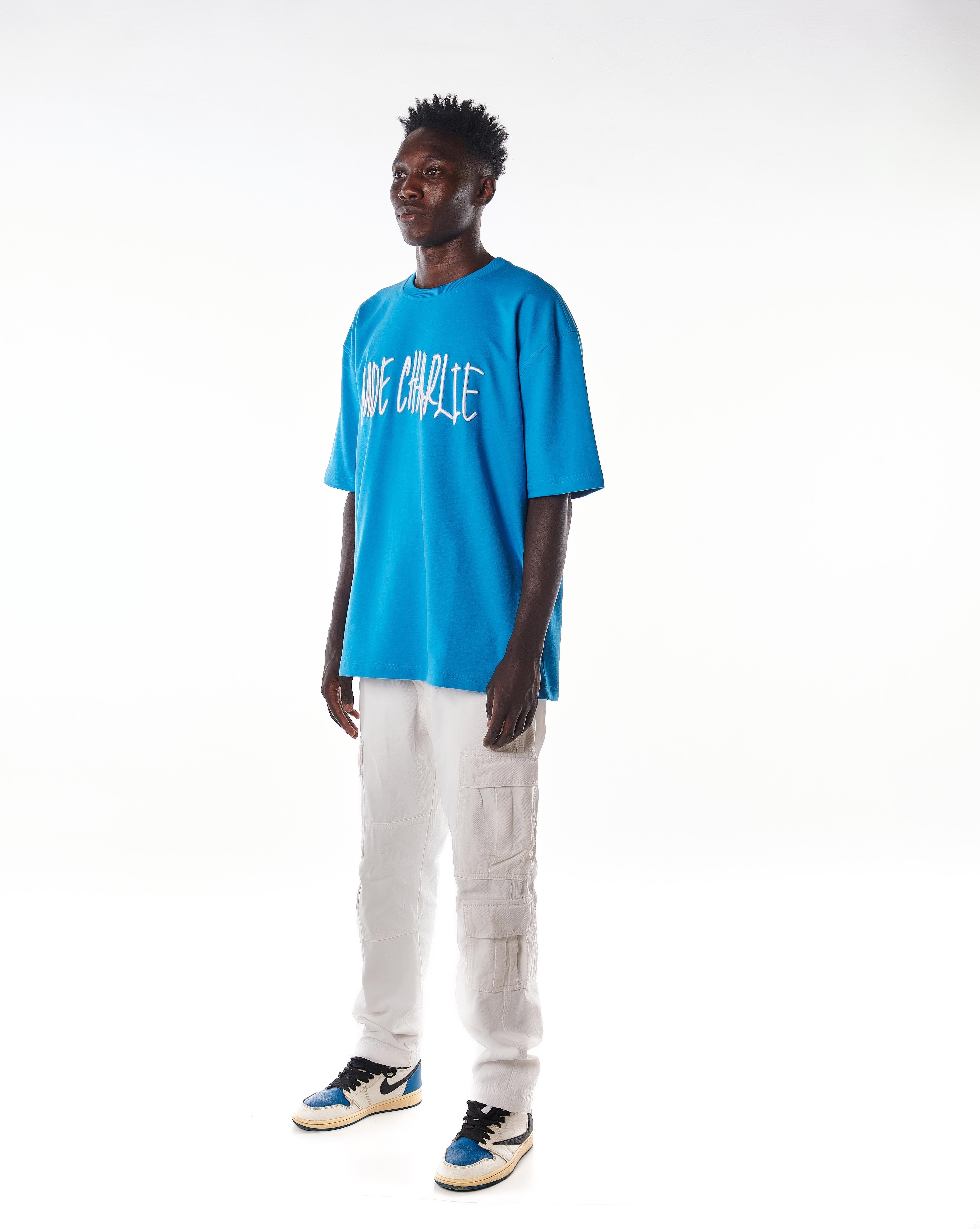 Dreiviertelansicht MOE CHARLIE Night Life T-Shirt, azurblauer Frontprint seitlich, Jordan Sneakers sichtbar