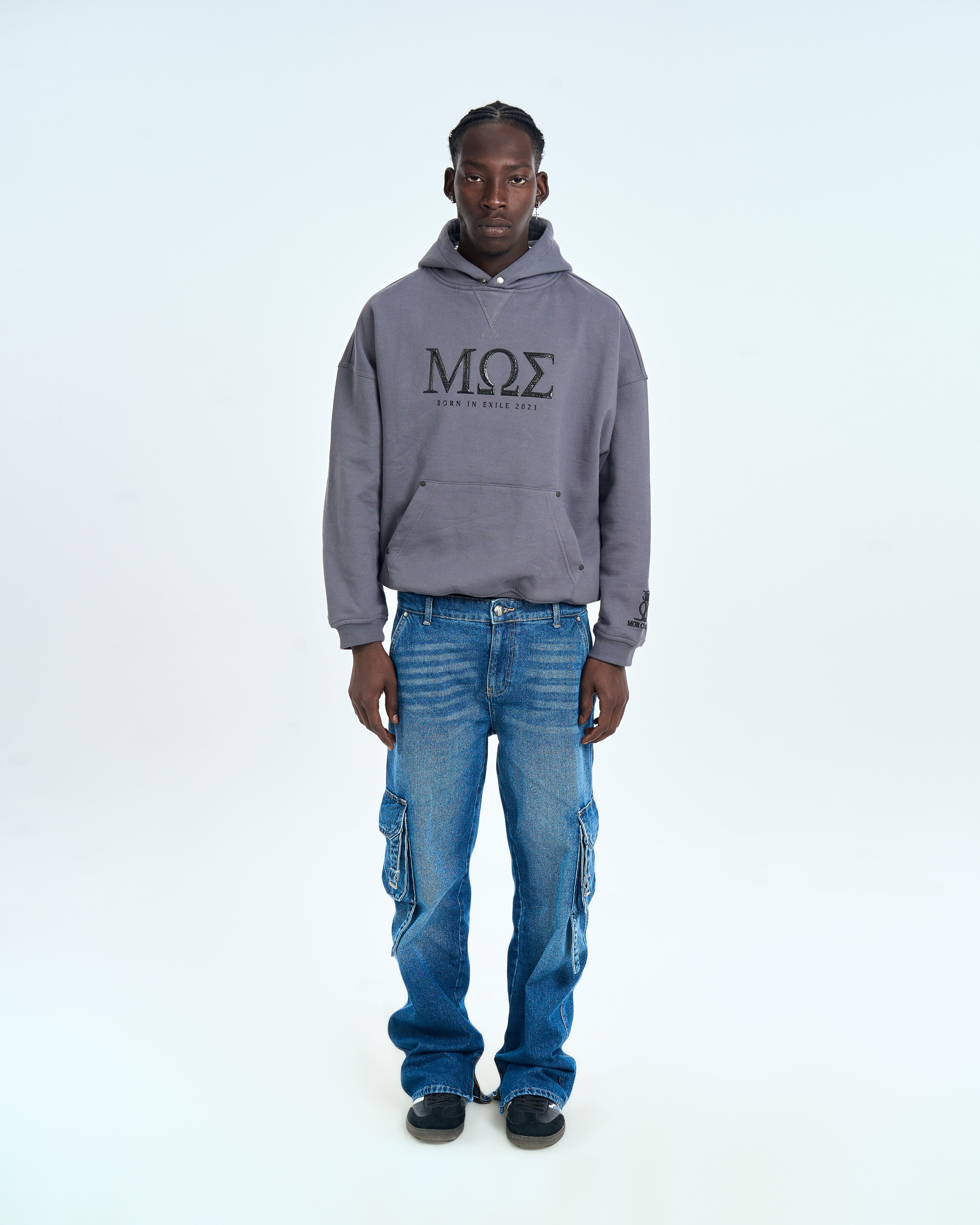 Born in Exile Hoodie MOE CHARLIE Grau, maennlicher Traeger, Ganzkoerperaufnahme mit Cargo-Jeans, Frontansicht