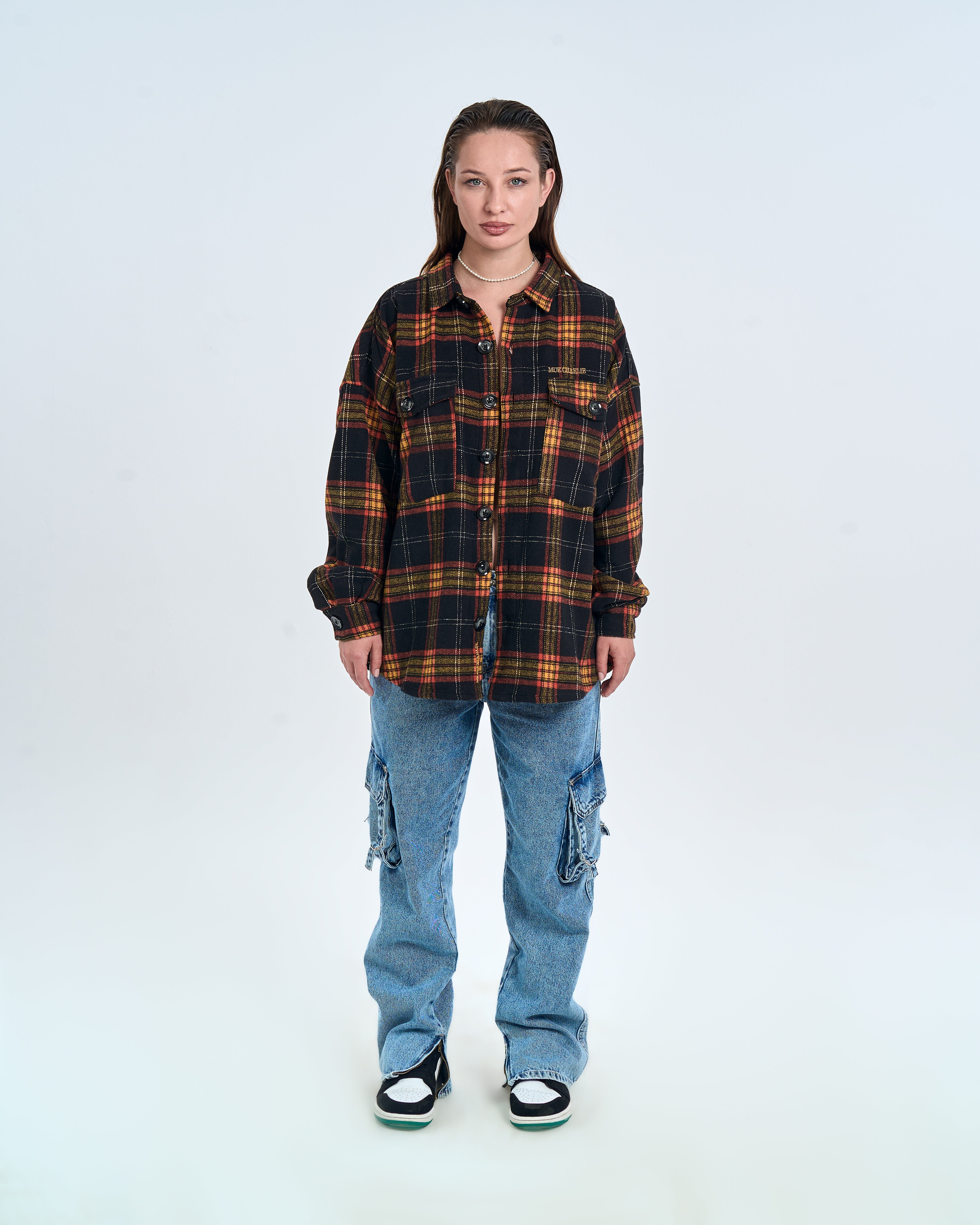 MOE CHARLIE Vintage Flannel Shirt, Frontansicht weiblich, Perlenkette, Cargo-Jeans und Air Jordan Sneakers
