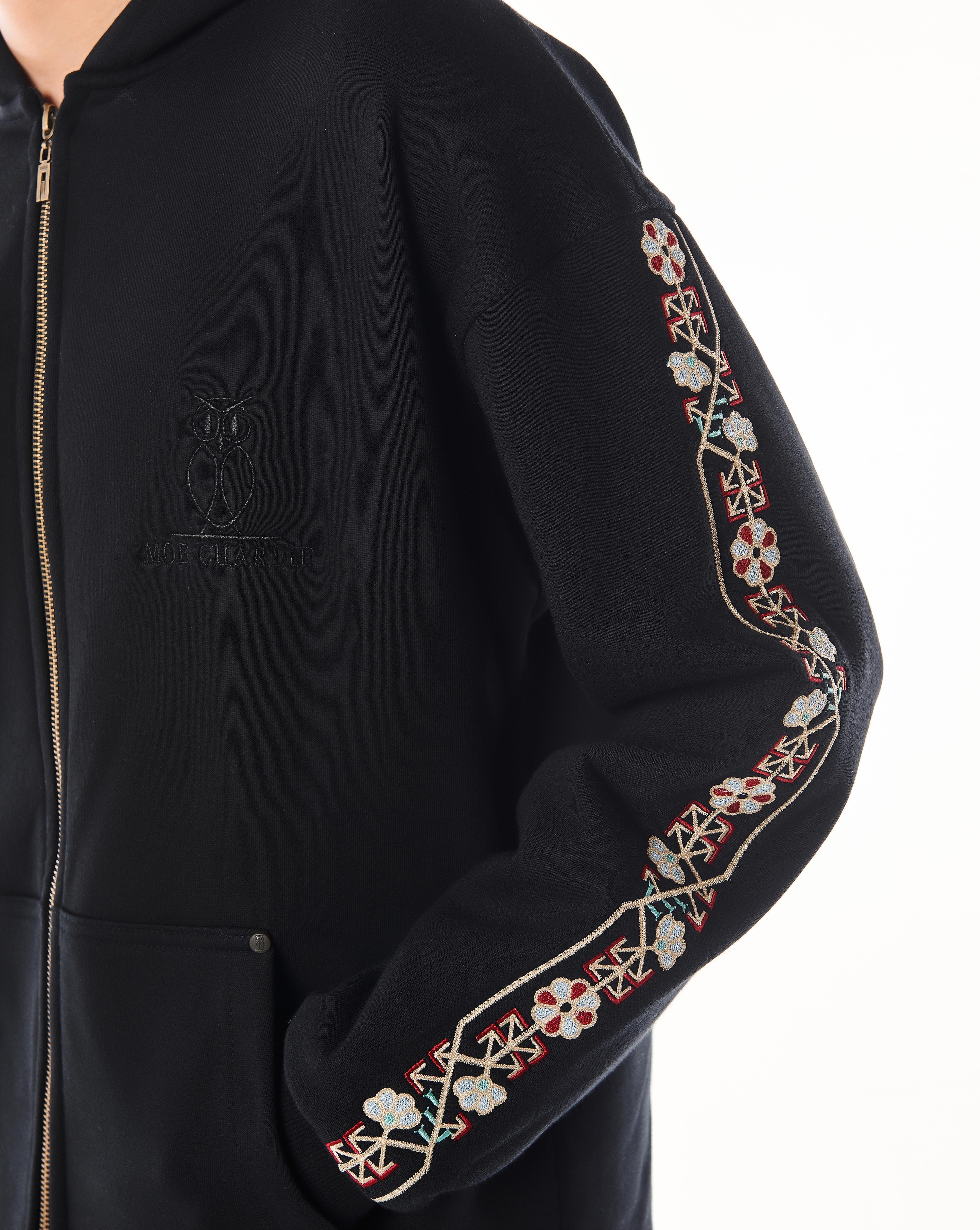 Nahaufnahme des ton-in-ton MOE CHARLIE Owl-Logos auf der linken Brust des schwarzen Culture Zip-Hoodies