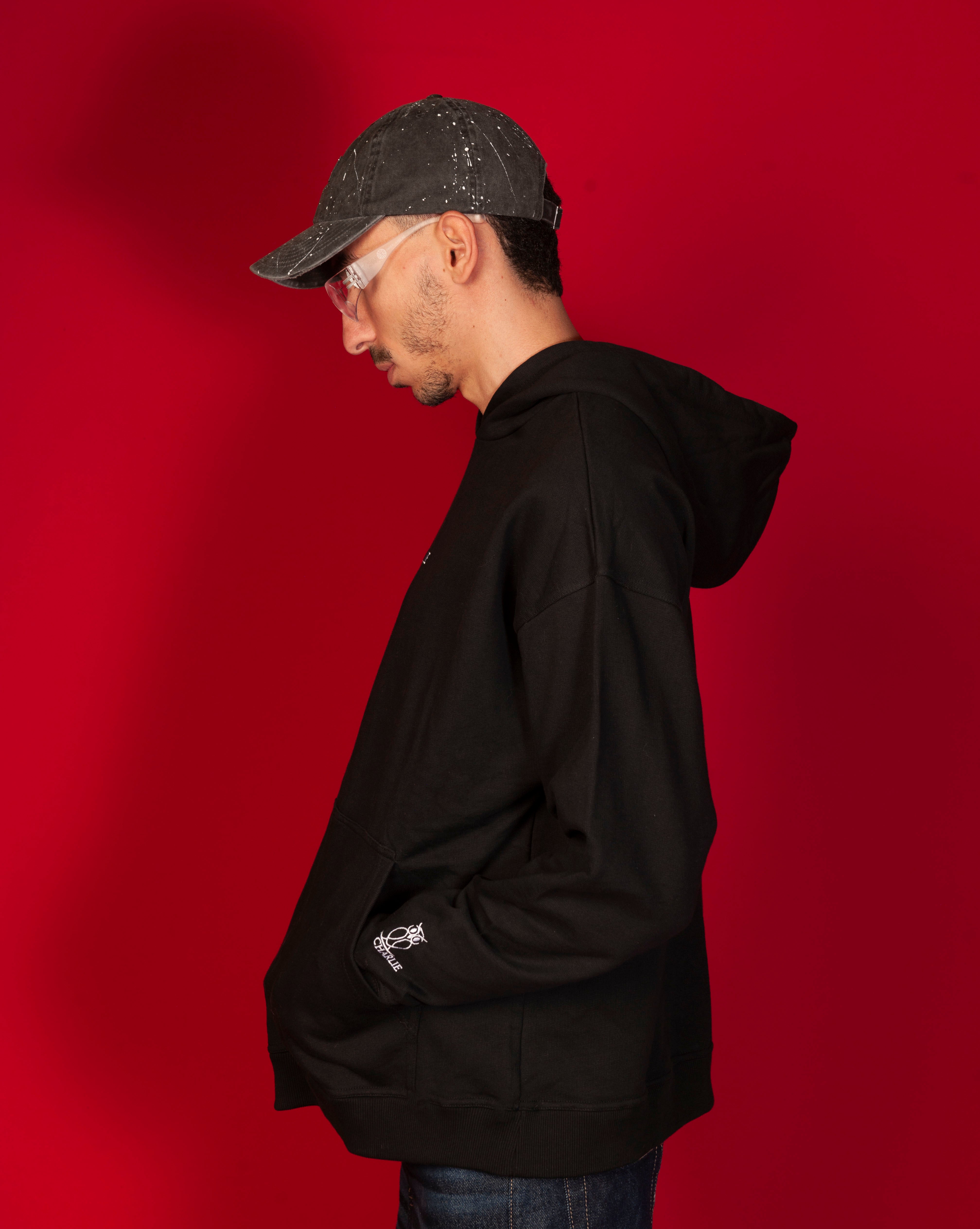 Seitenansicht Basic 460 Hoodie MOE CHARLIE, schwarzer Oversize-Hoodie, weisses Owl-Logo am Aermelbund sichtbar