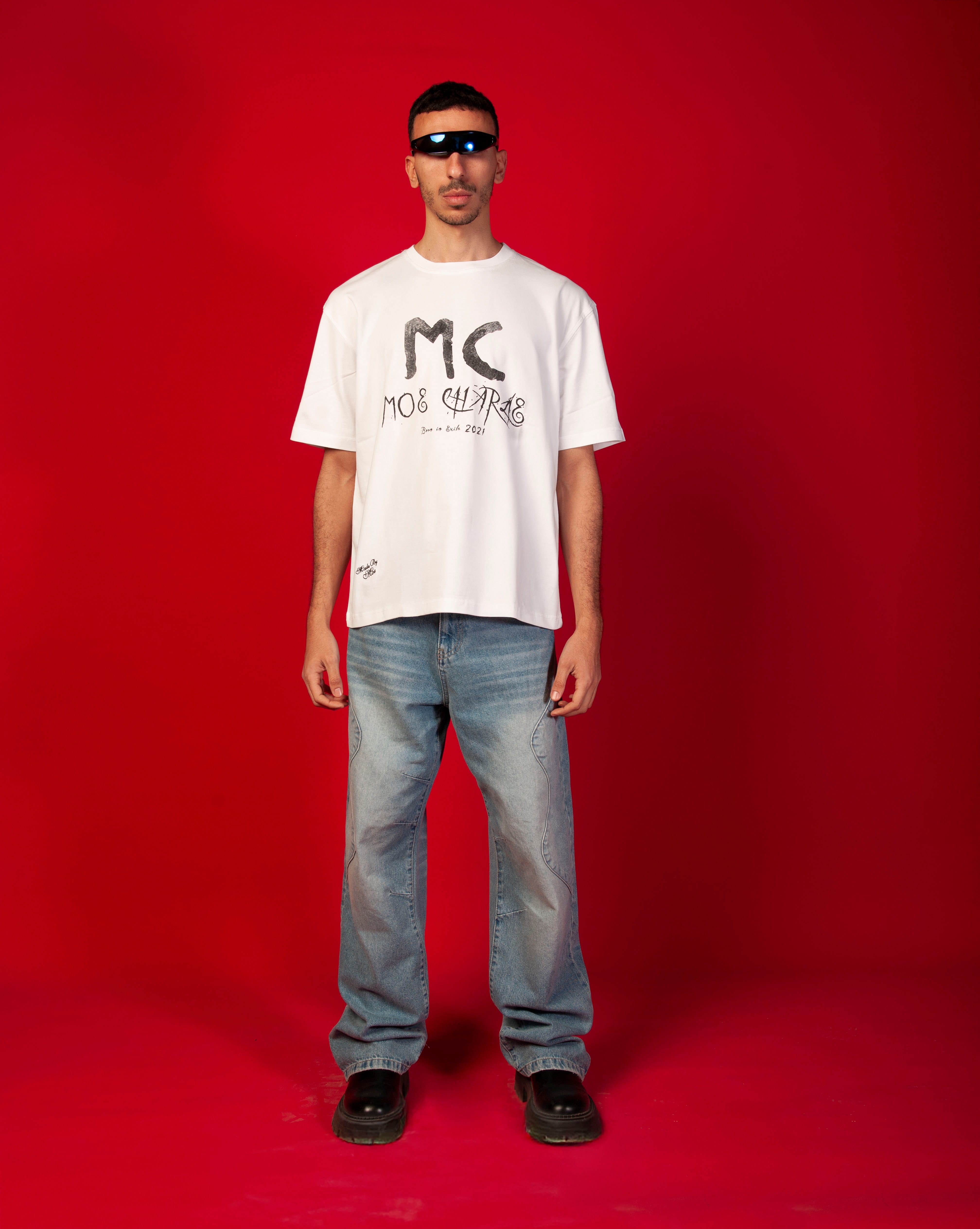 MC T-Shirt MOE CHARLIE Frontansicht Ganzkoerper, weisses Tee mit MC-Print, helle Jeans und schwarze Chunky-Boots
