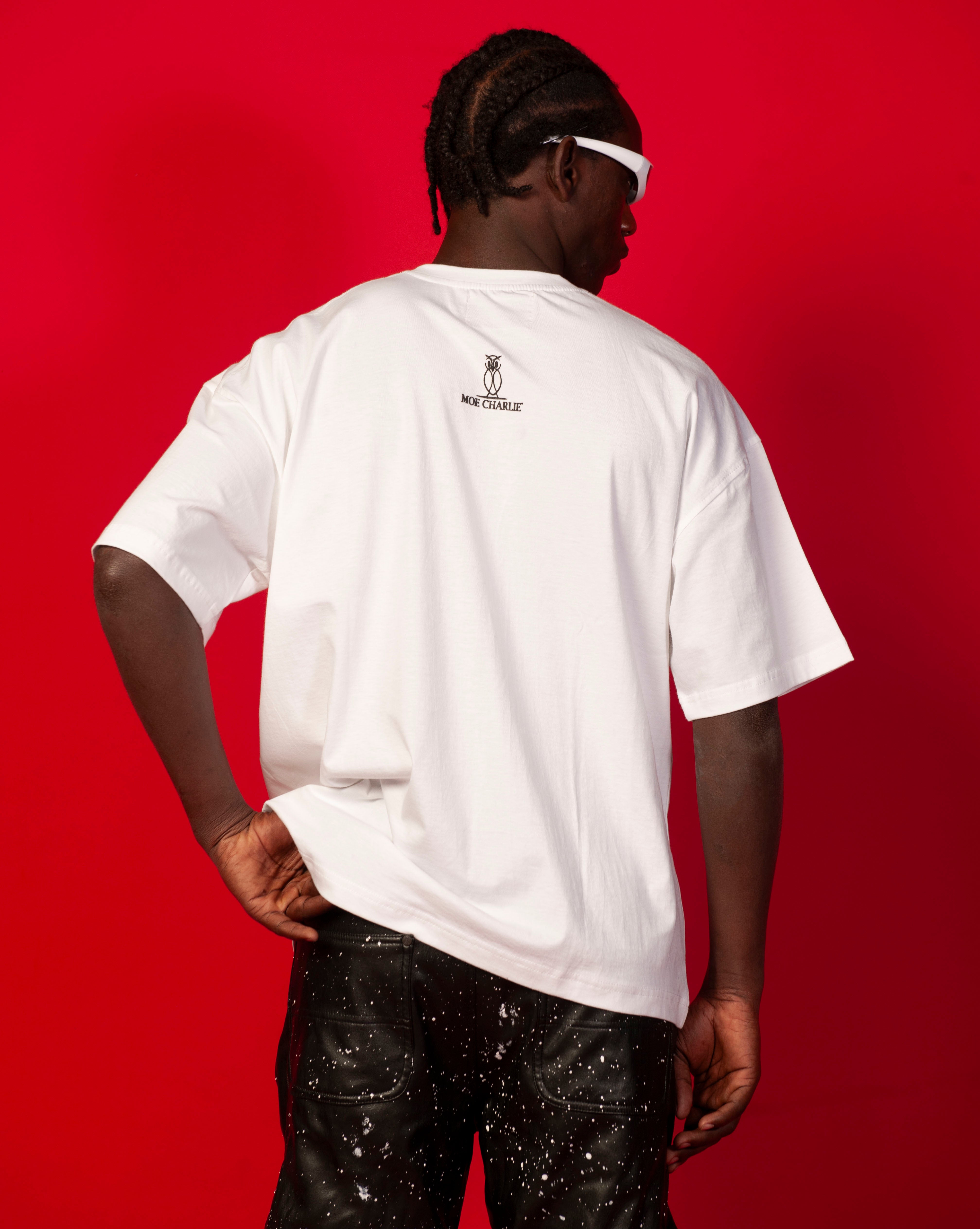 Rueckenansicht Moe T-Shirt Weiss MOE CHARLIE, dunkles Owl-Logo auf weisser Rueckseite, schwarze Spritzer-Lederhose