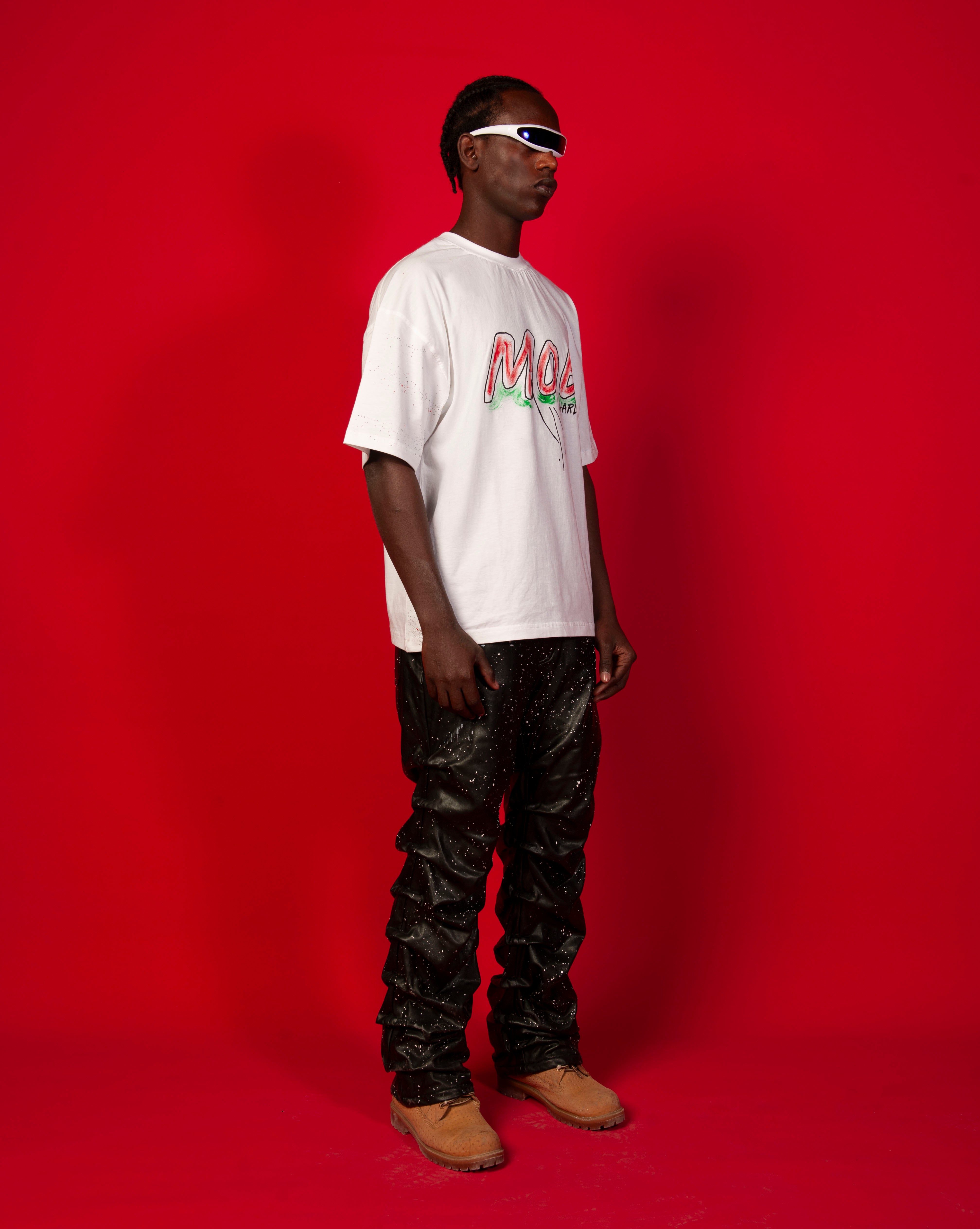 Moe T-Shirt Weiss MOE CHARLIE, Seitenansicht maennlich, weisses Graffiti-Tee, schwarze Glanz-Lederhose, Camel-Boots