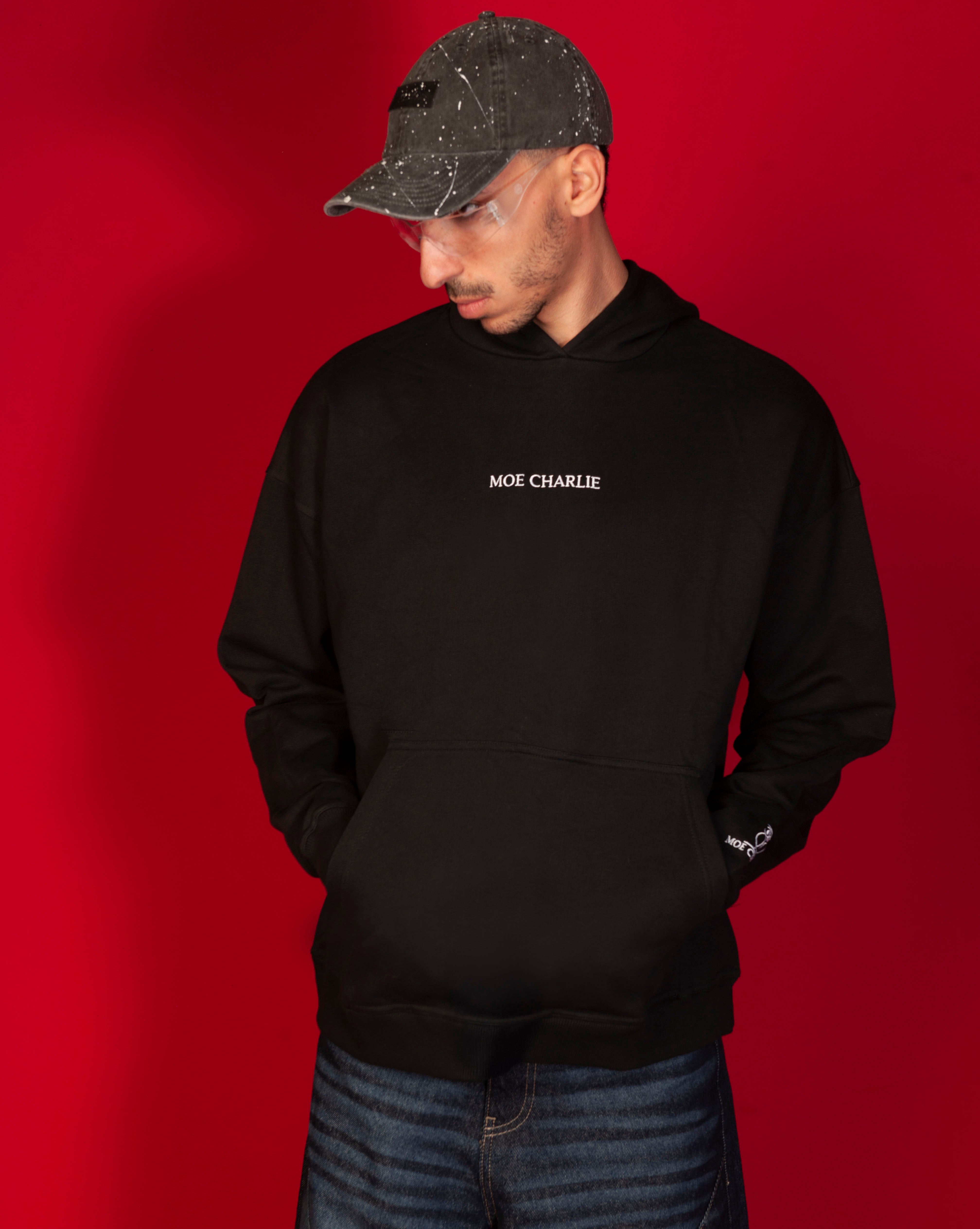 MOE CHARLIE Basic 460 Hoodie Frontansicht, schwarzer Hoodie mit weissem Stick-Schriftzug, maennlich Blick nach unten