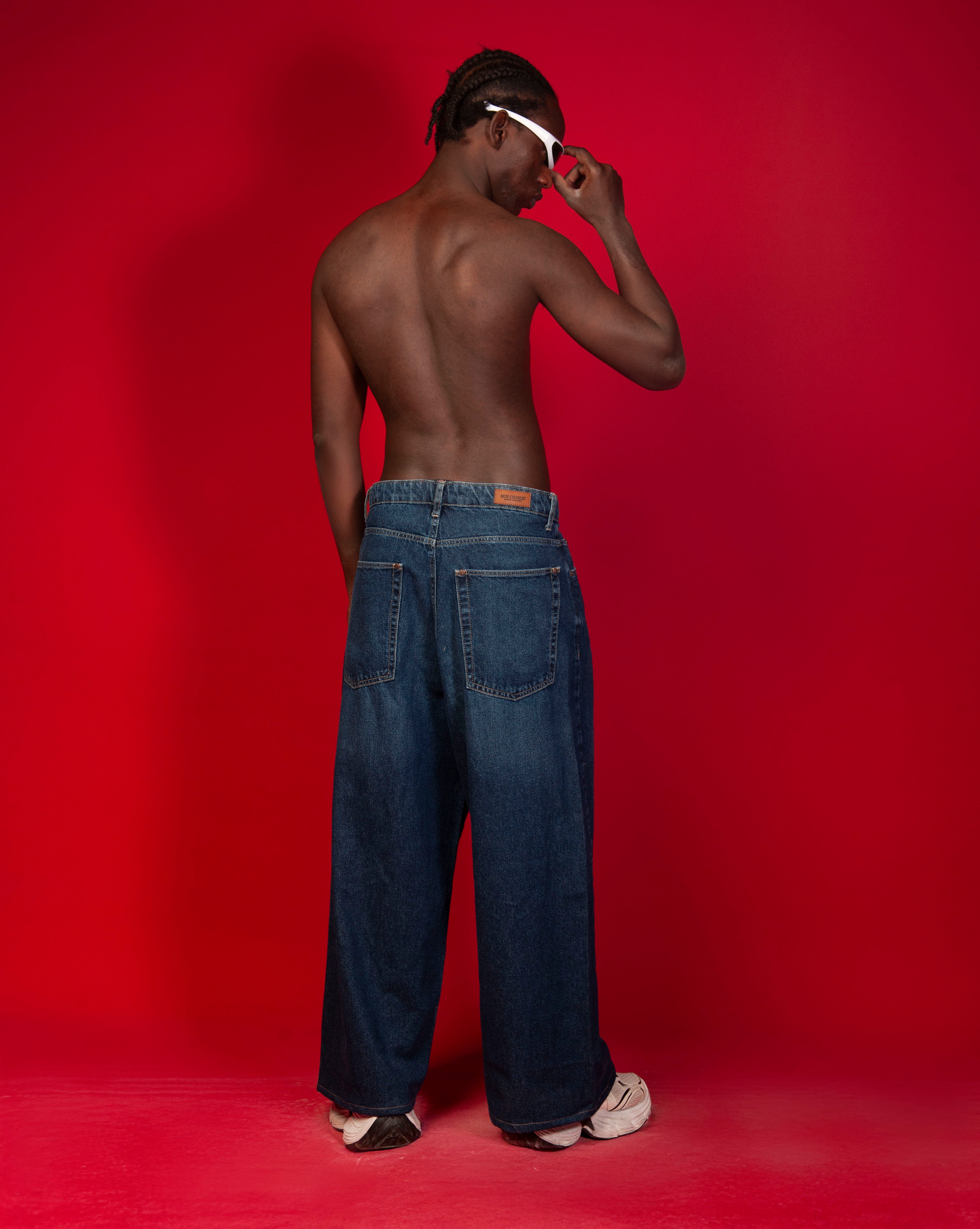 Extra Baggy Denim Blau MOE CHARLIE, Rueckenansicht maennlich, Hand an Brille, Leder-Label am Bund