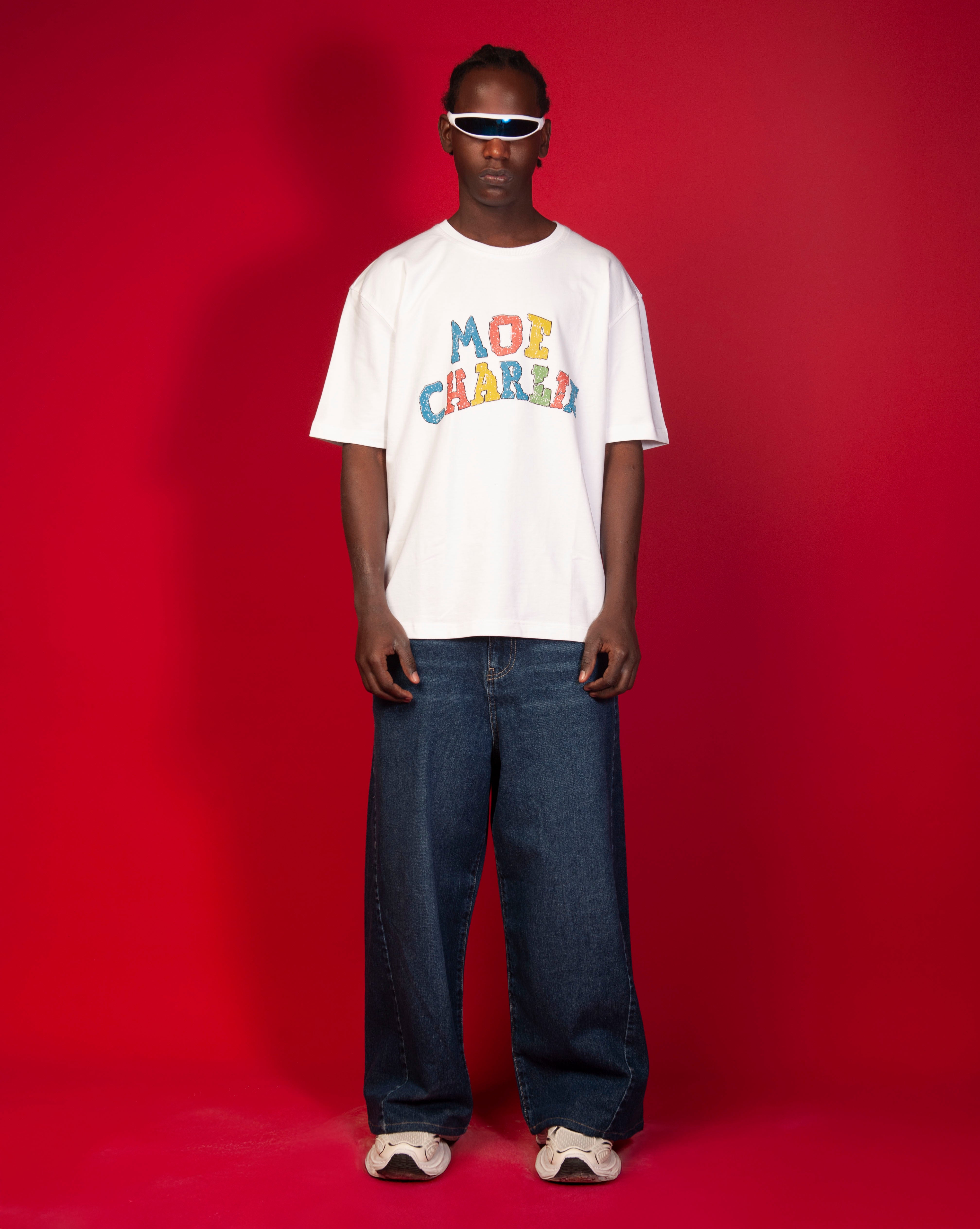 Google T-Shirt MOE CHARLIE Frontansicht, maennlich, bunter Block-Print, weisser Visor und dunkle Navy-Jeans