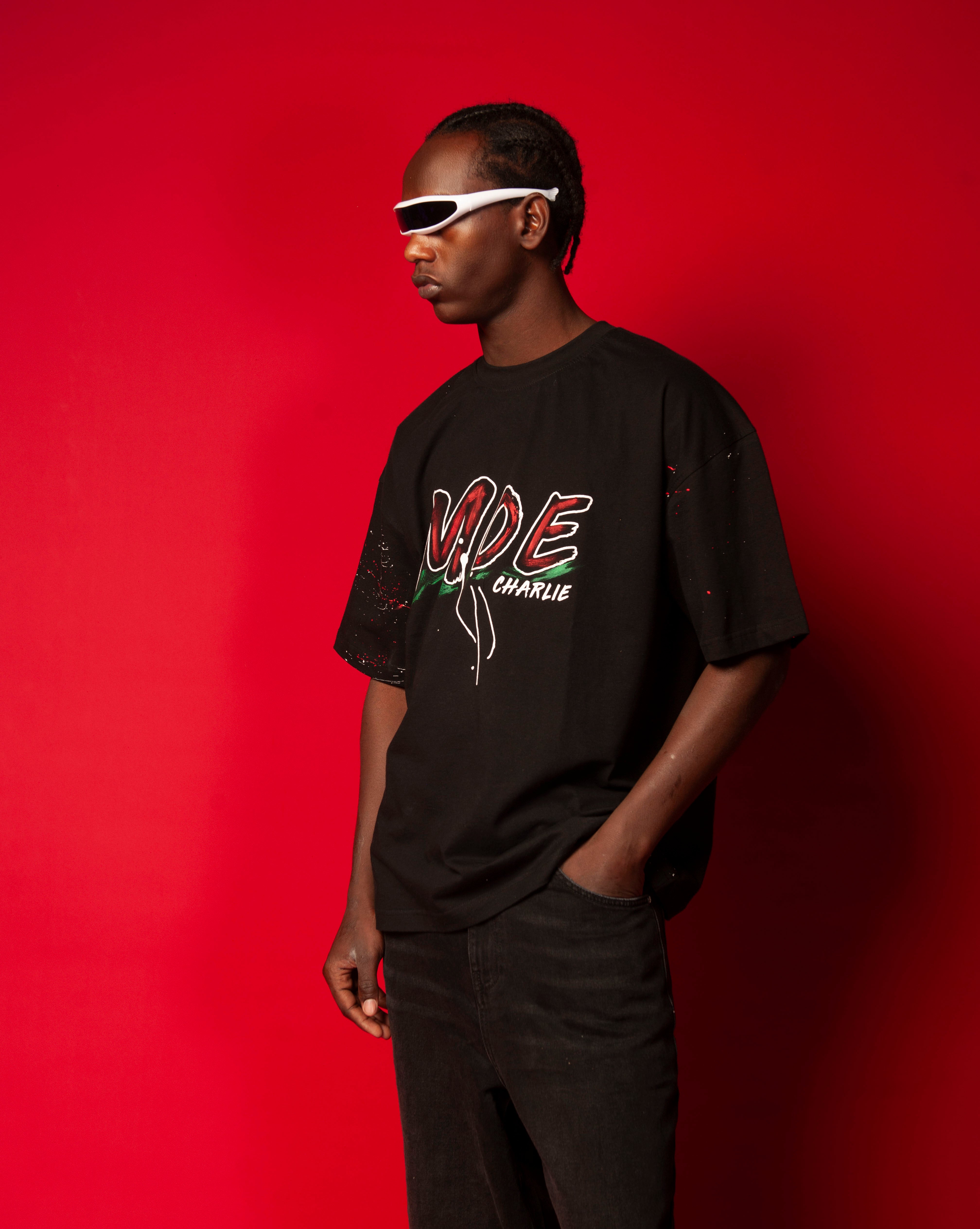 Moe T-Shirt Schwarz MOE CHARLIE, Dreiviertelansicht seitlich, roter Graffiti-MOE-Print, schwarze Hose