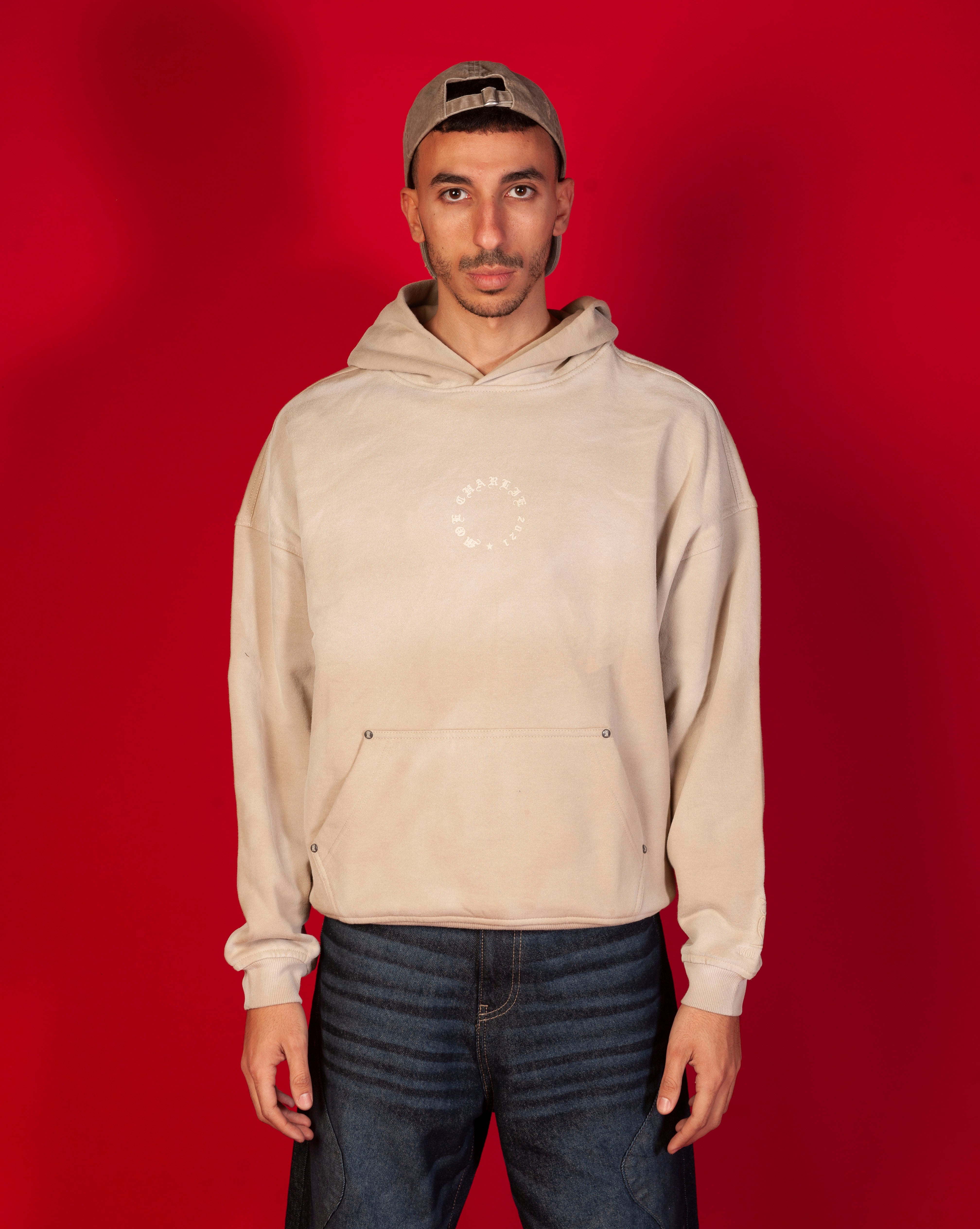 Faded MOE CHARLIE Hoodie, Frontansicht Ganzkoerper maennlich, sand-beige verwaschener Hoodie mit Kreis-Logo, Kappe