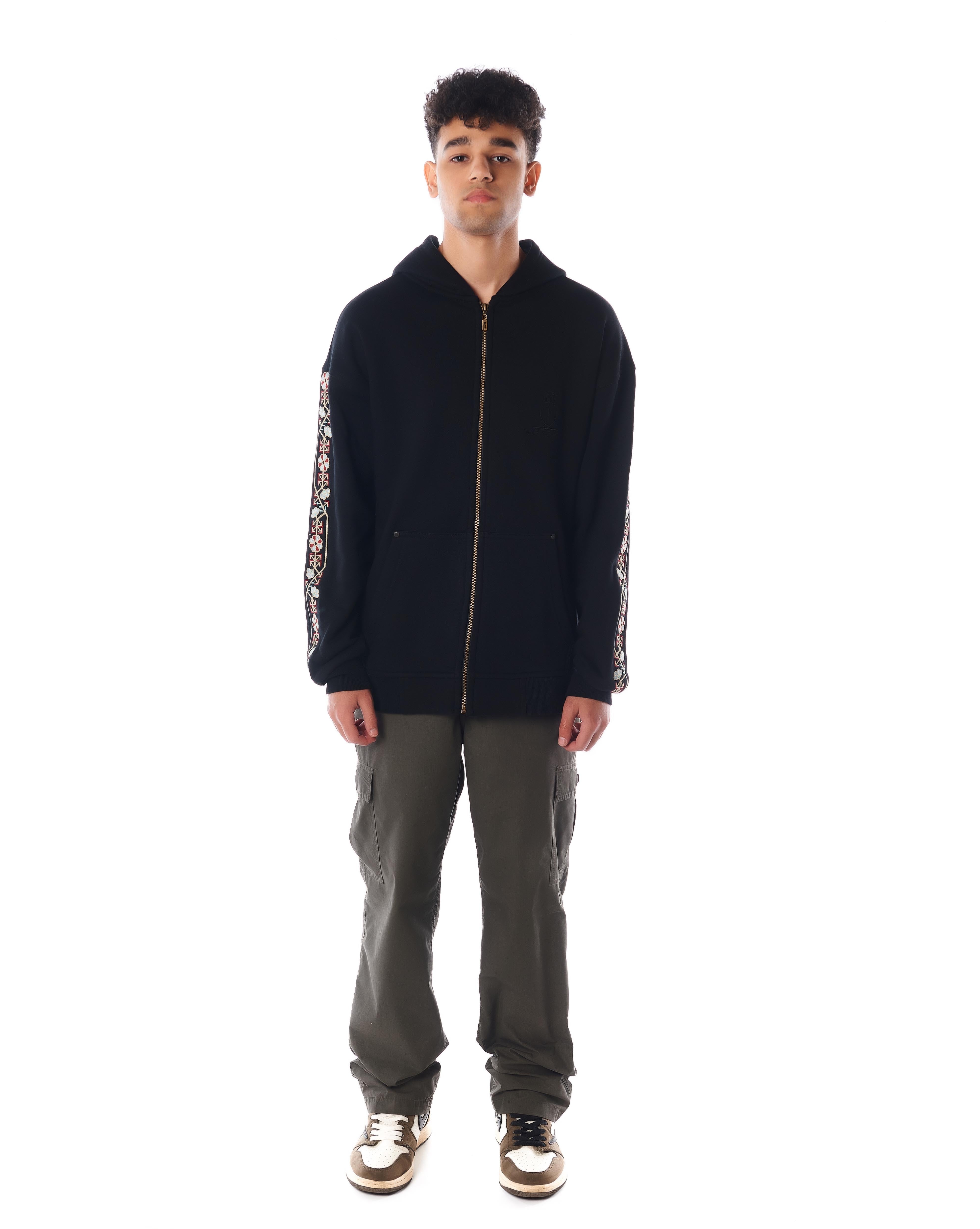 MOE CHARLIE Culture Zip-Hoodie in Schwarz, Frontpose mit Goldreißverschluss und floraler Stickerei an beiden Ärmeln