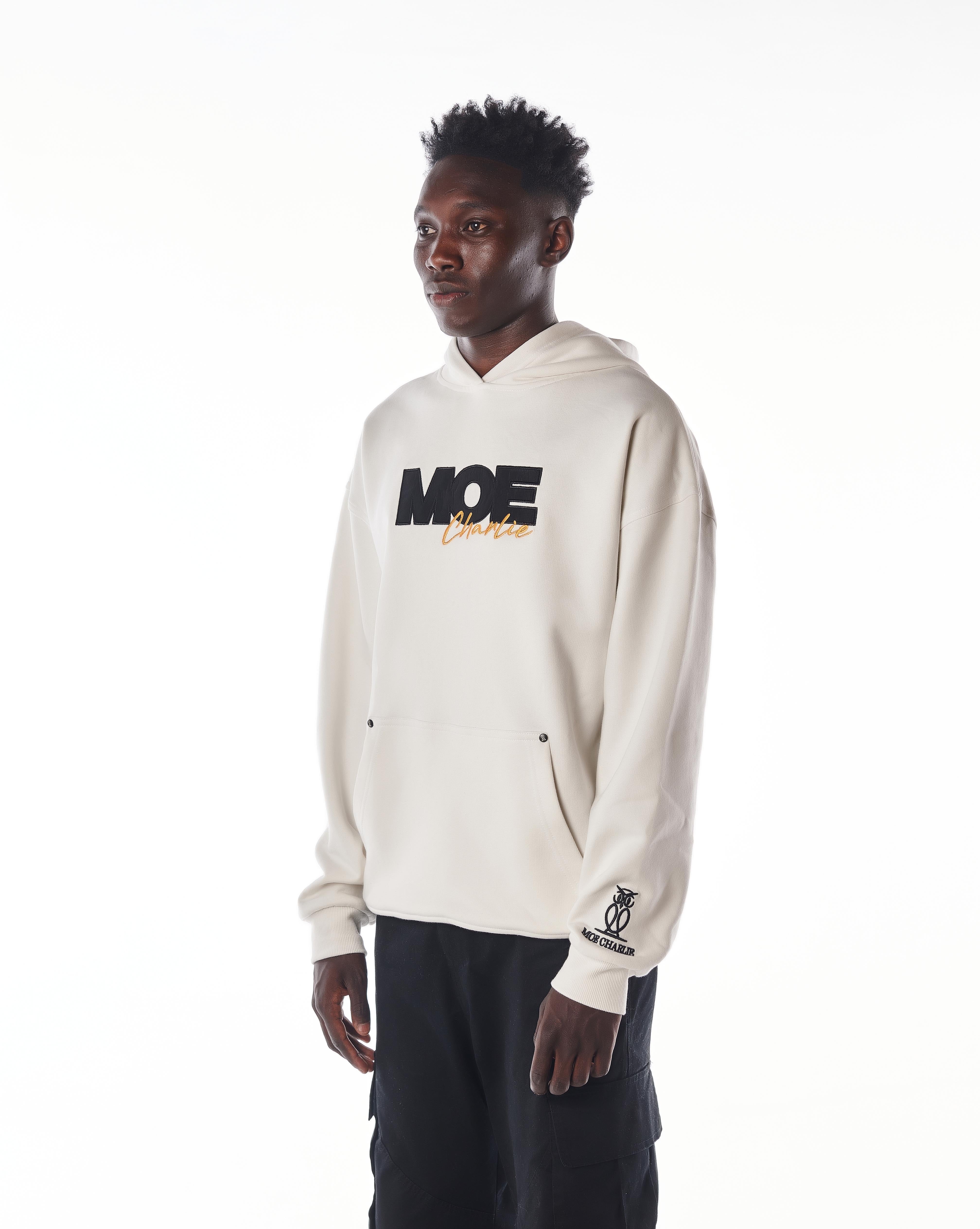 Dreiviertelansicht MOE CHARLIE Gold Passion Hoodie, Frontprint und Eulen-Ärmel-Logo, schwarze Cargo-Hose