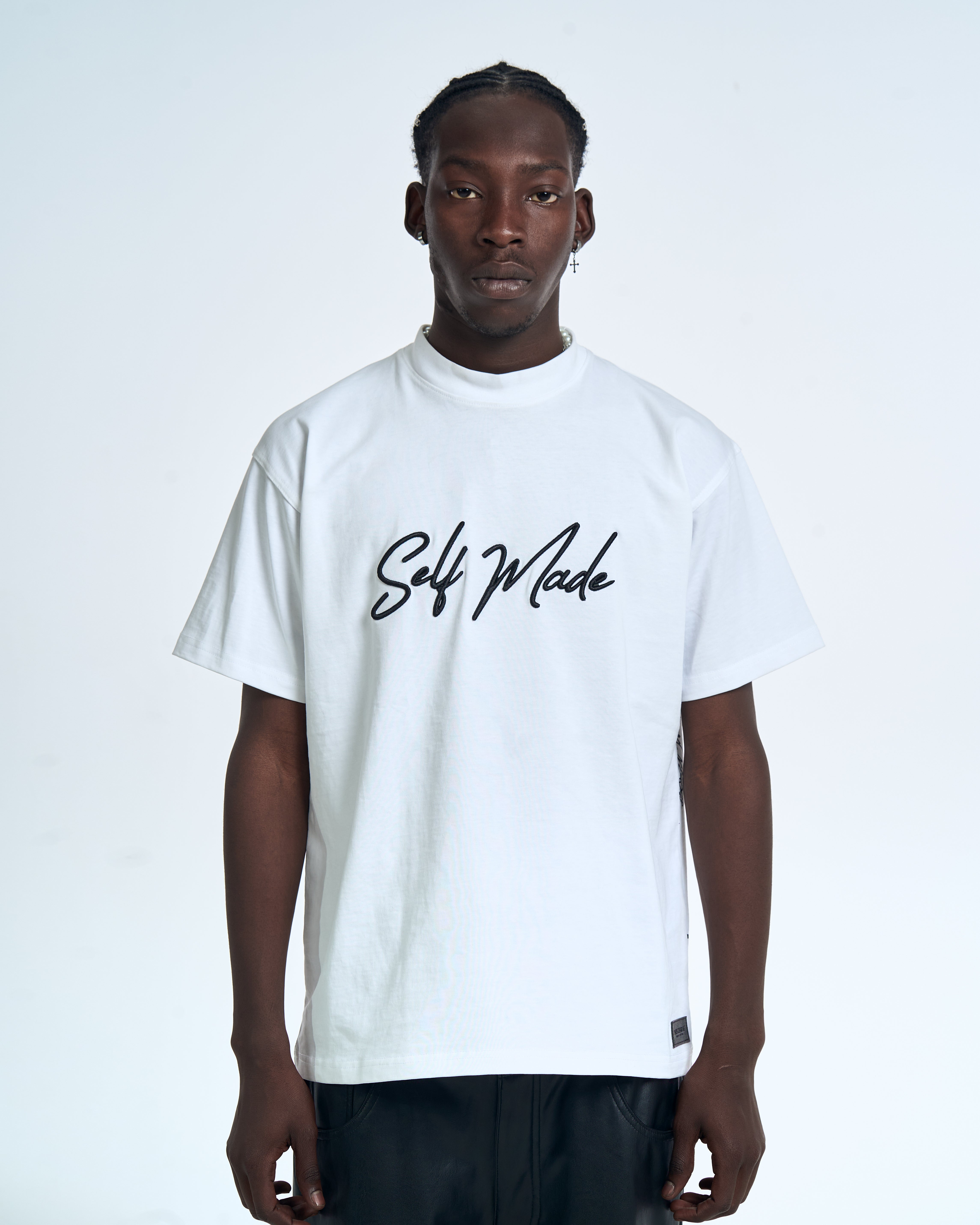 Close-up Frontansicht MOE CHARLIE Self Made Shirt – schwarzes Brush-Lettering Self Made zentriert auf weißem Stoff