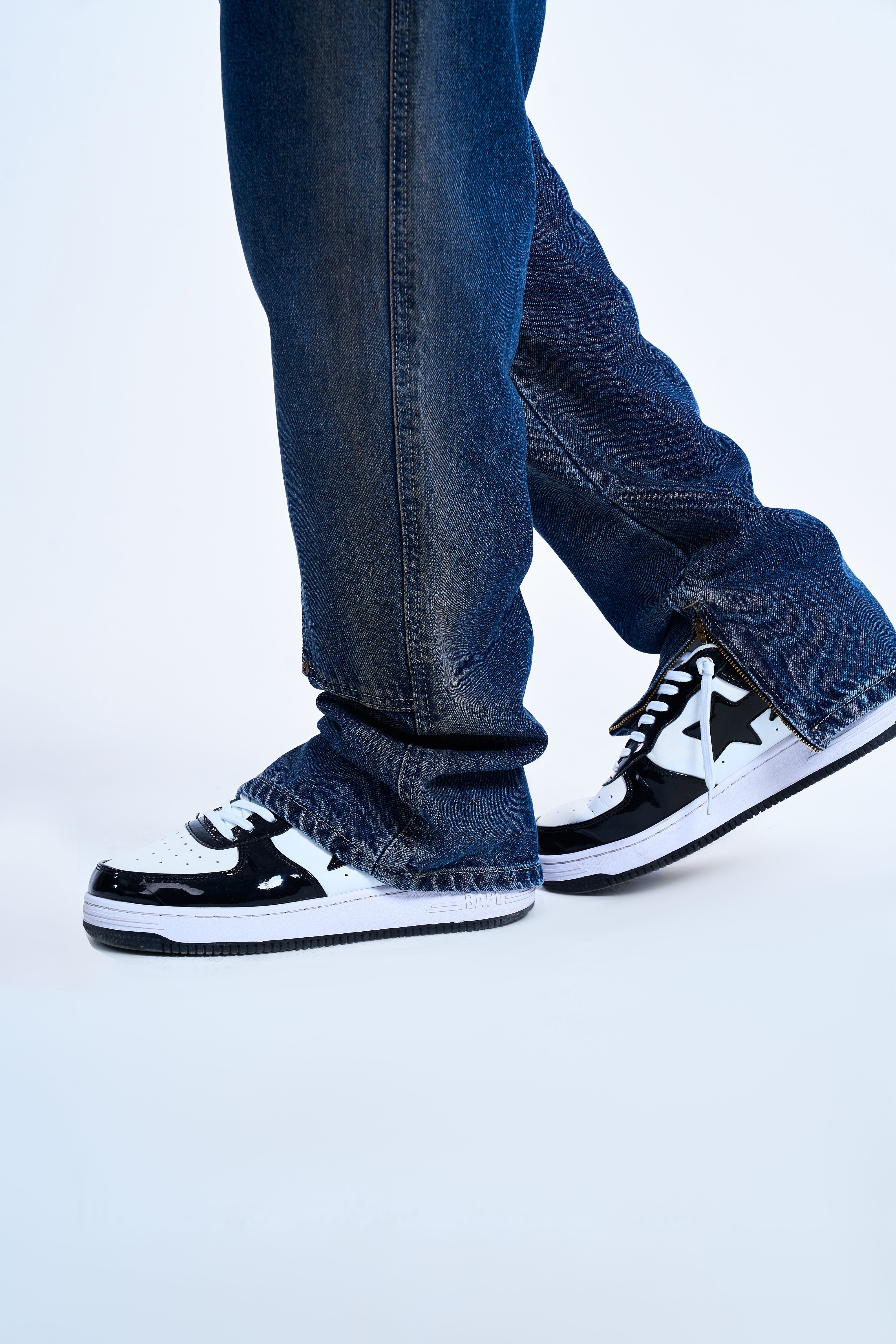 Saum-Detail der MOE CHARLIE Double Knee Flare Denim – Knöchel-Zipper geöffnet, kombiniert mit BAPE-Sneakers