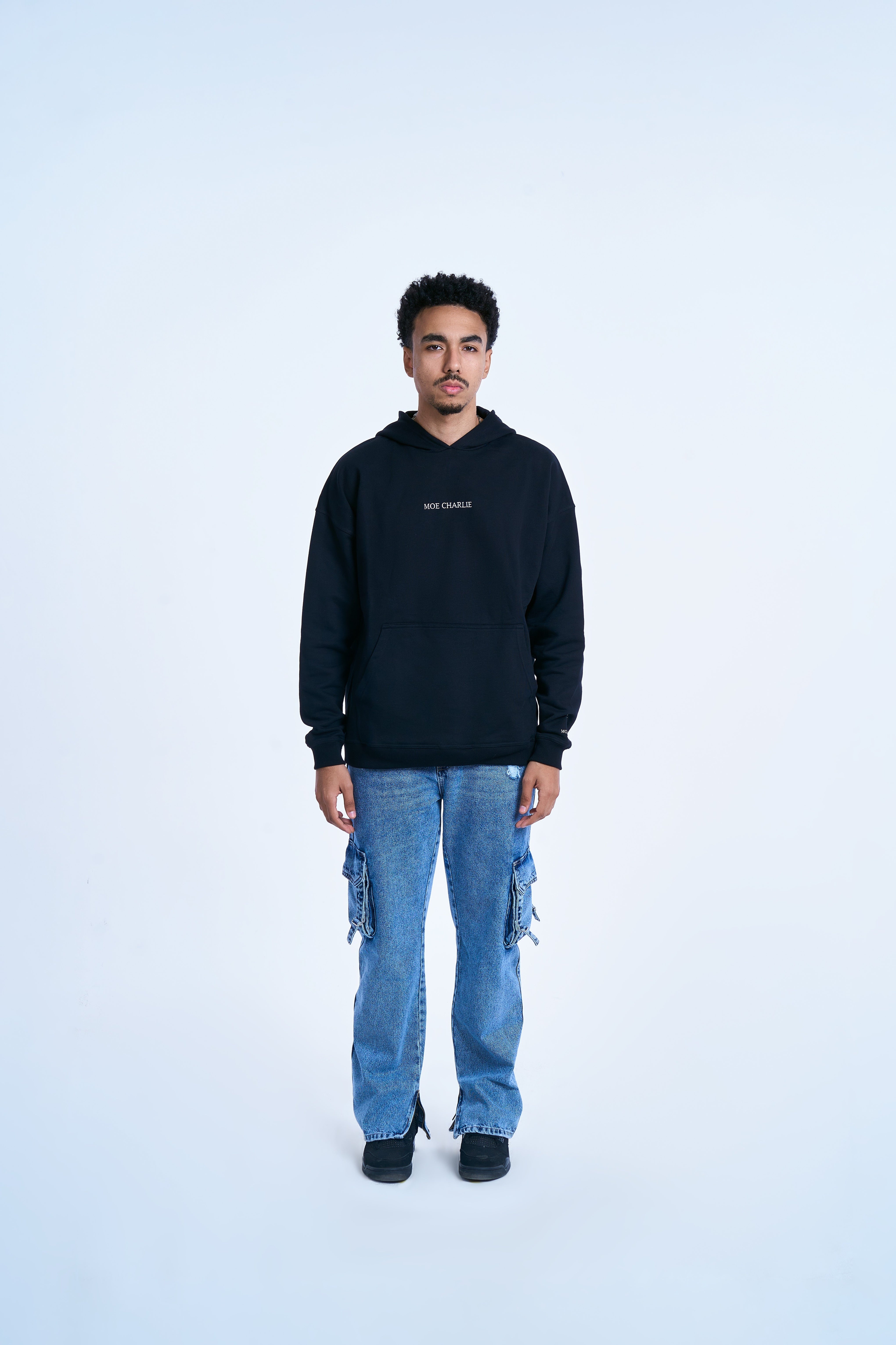 MOE CHARLIE Hoodie Schwarz, Frontansicht maennlich mit weissem Stick auf der Brust, Cargo-Jeans