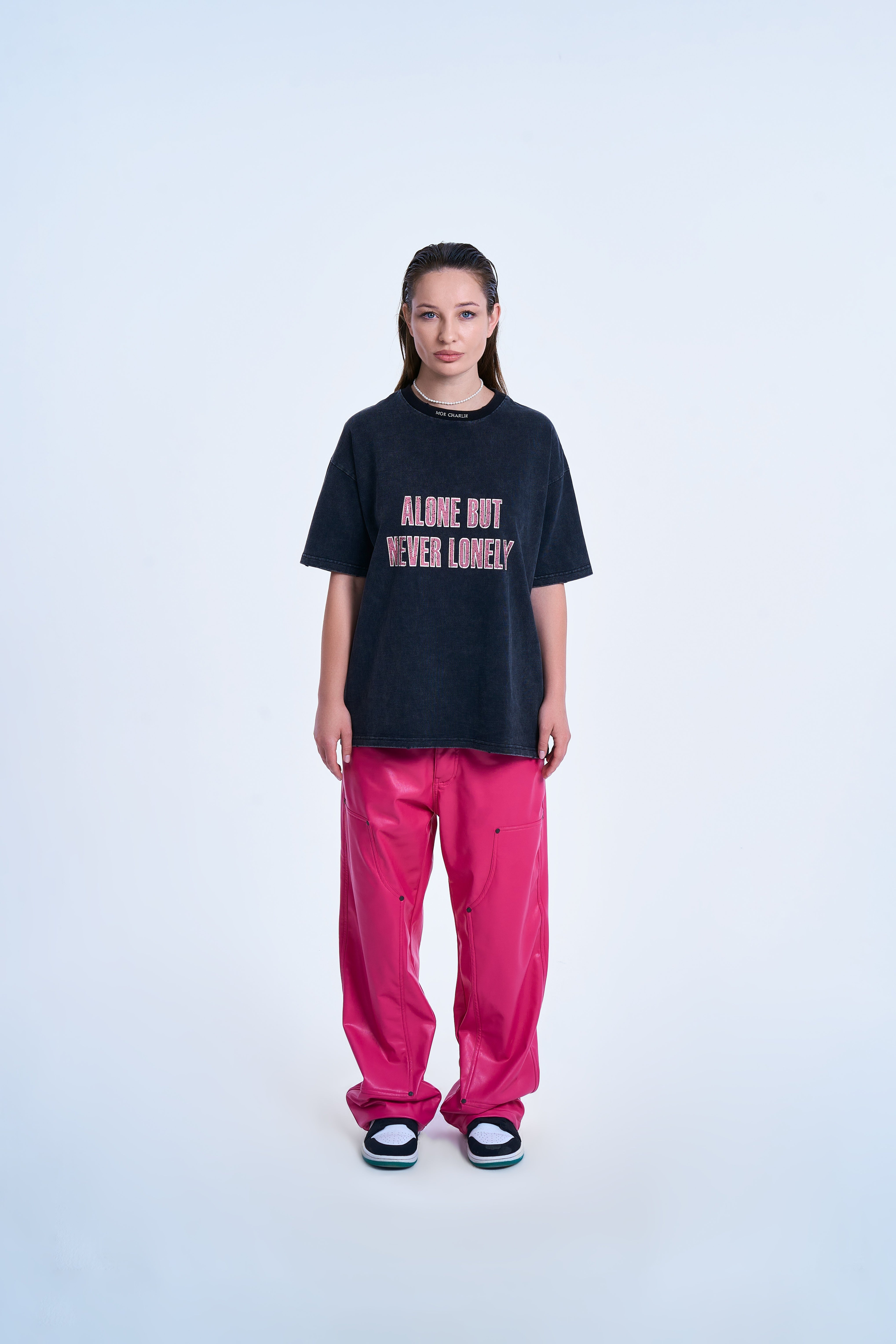MOE CHARLIE Never Lonely T-Shirt – Frontansicht Damenmodel, Acid-Washed-Tee, Hot-Pink-Lederhose, Jordan-Sneaker