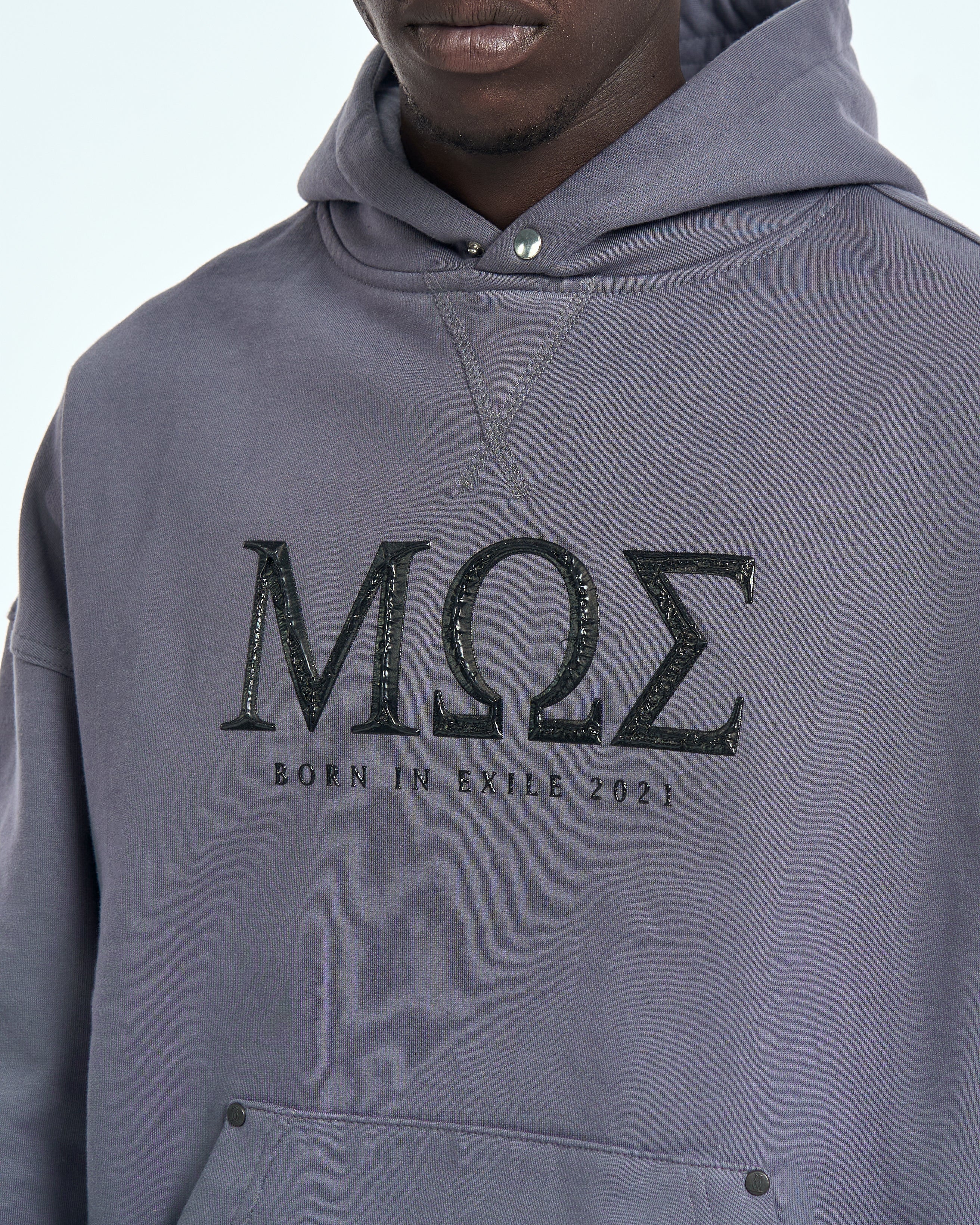 Detailaufnahme MOS Born in Exile 2021 Frontprint auf grauem MOE CHARLIE Hoodie, Druckknopf an der Kapuze