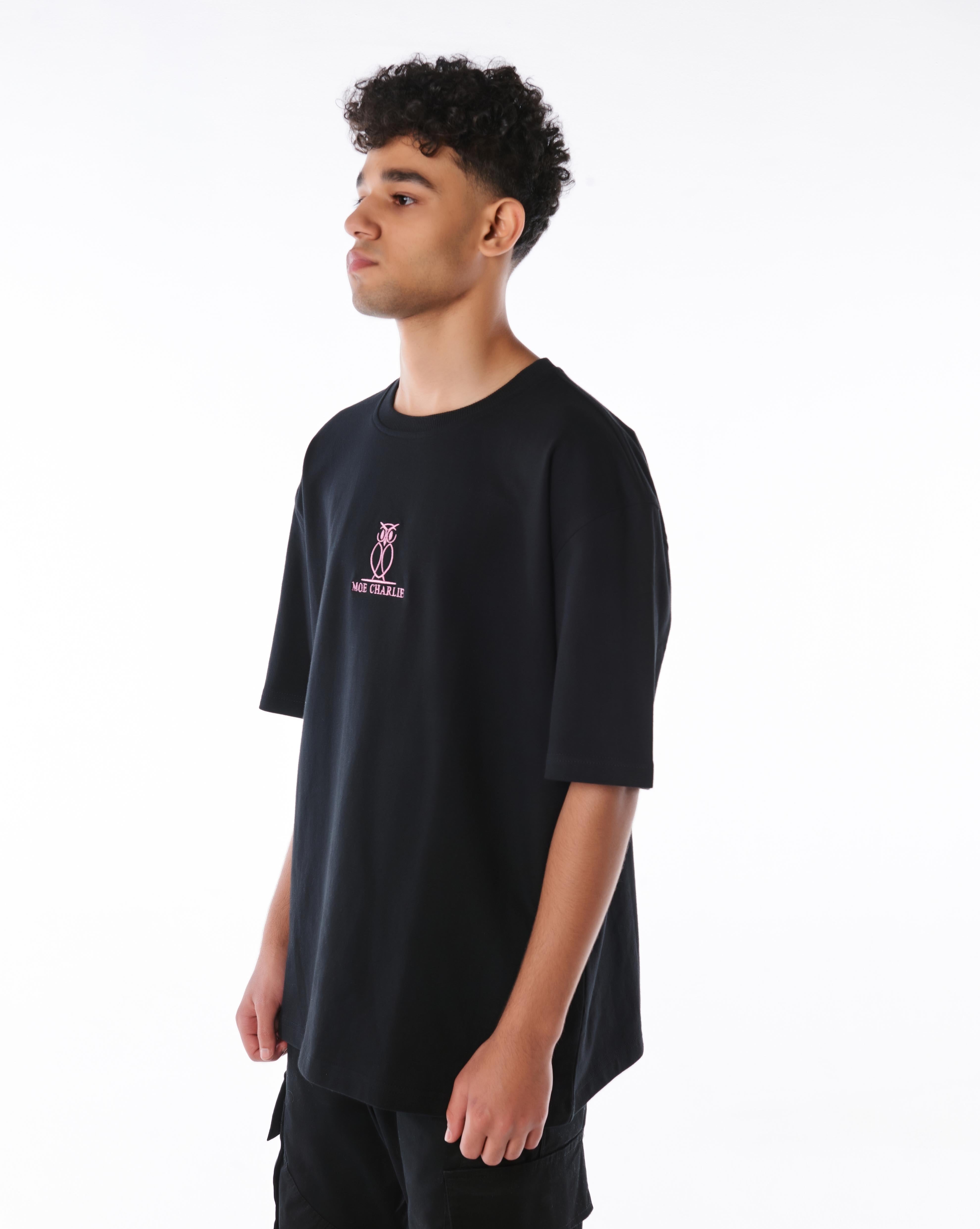 MOE CHARLIE Pink Logo T-Shirt in Schwarz, seitliche Dreiviertelansicht, rosafarbene Owl-Stickerei auf der Brust sichtbar