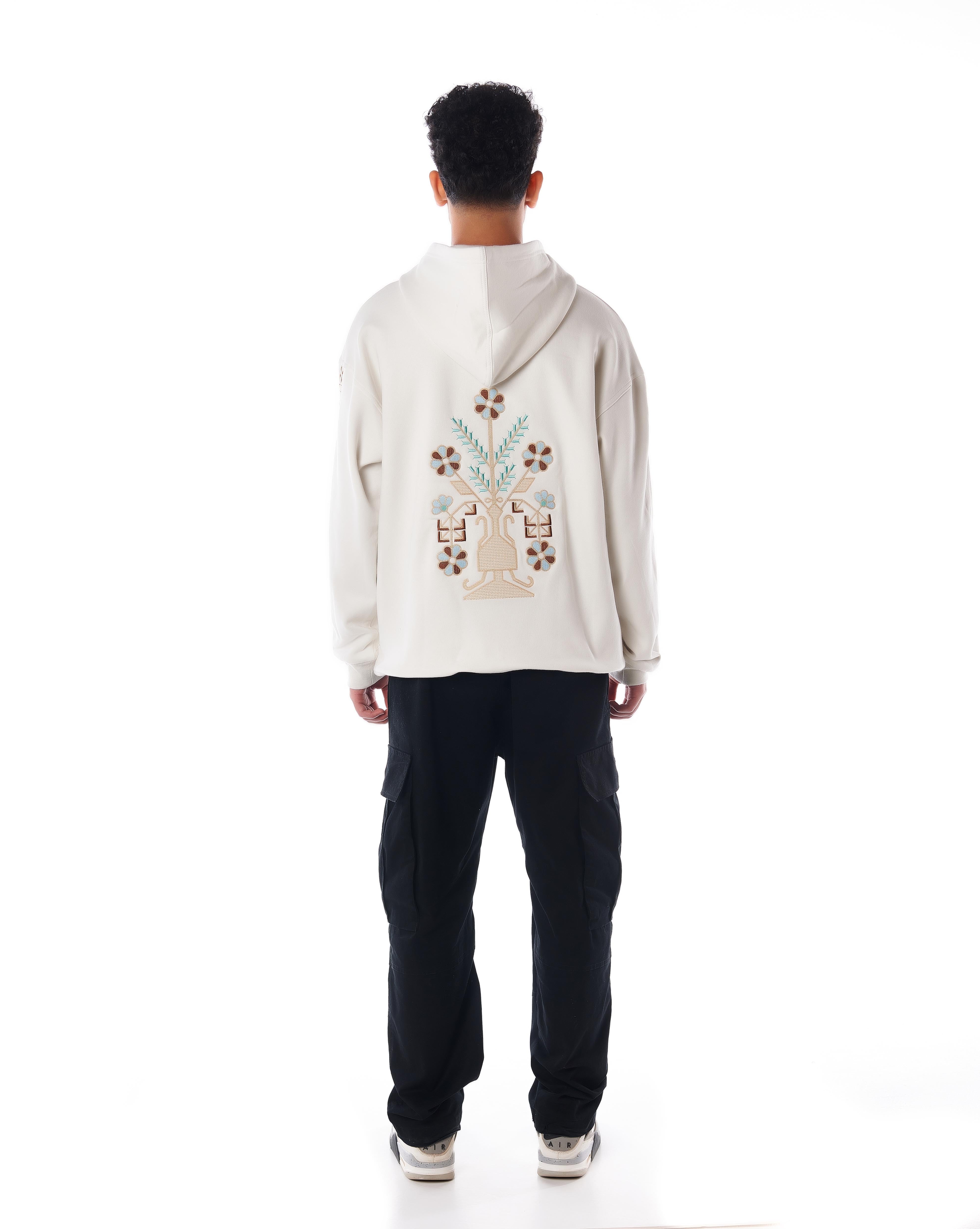 Rückenansicht des MOE CHARLIE Star White Hoodies, großes ornamentales Vasen-Stickmotiv in Braun und Blaugrün auf Creme