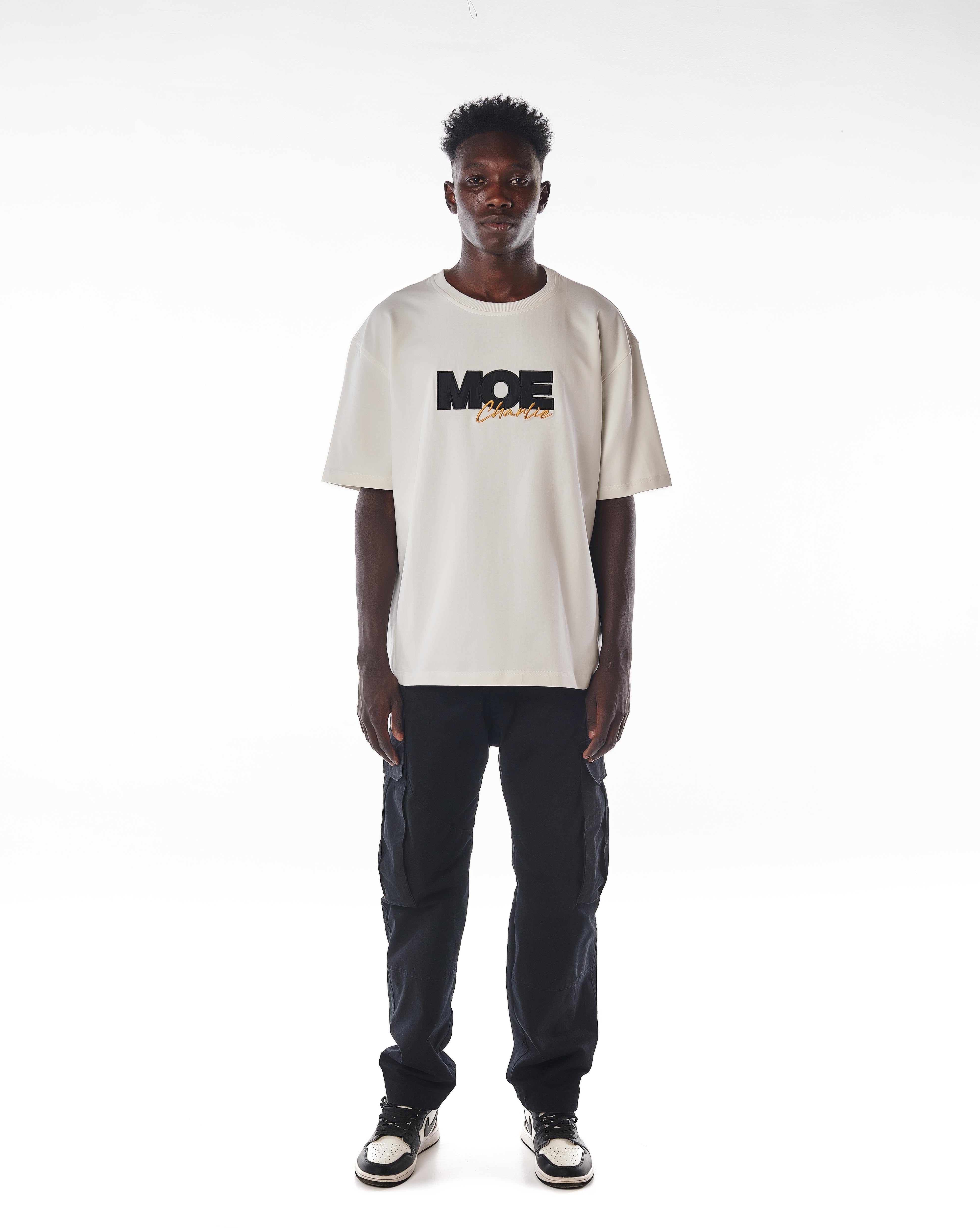 Frontansicht MOE CHARLIE Gold Passion T-Shirt in Creme, schwarze MOE-Stickerei mit goldenem Charlie-Schriftzug