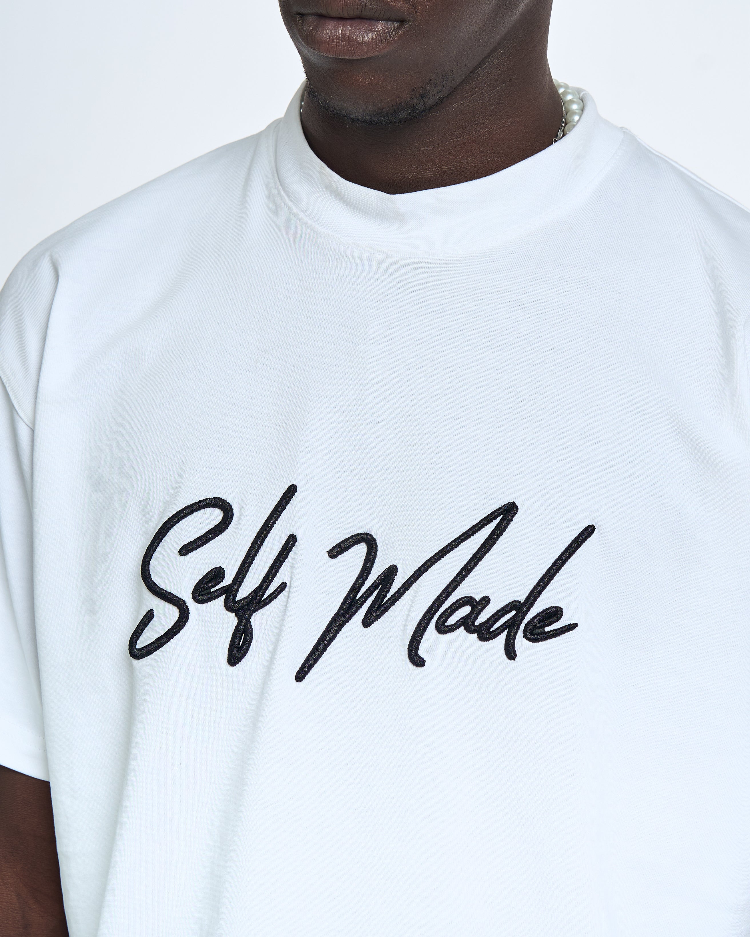 Detailaufnahme Brustprint MOE CHARLIE Self Made – gebürstetes schwarzes Script-Logo Self Made auf weißem Tee