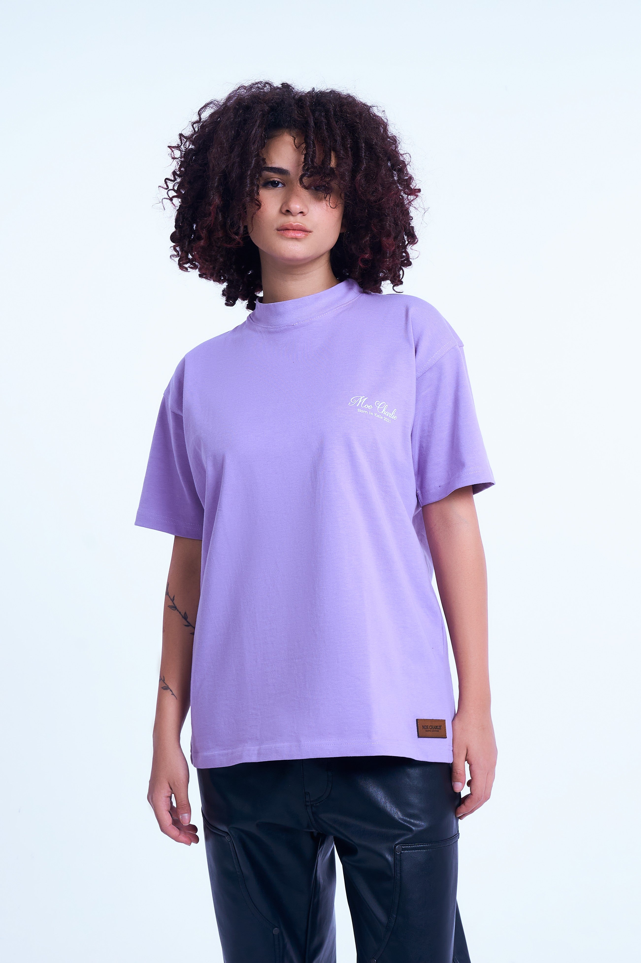 MOE CHARLIE Lavendel T-Shirt weiblicher Model 3/4-Front – Script-Brustlogo und Leder-Patch am Saum erkennbar