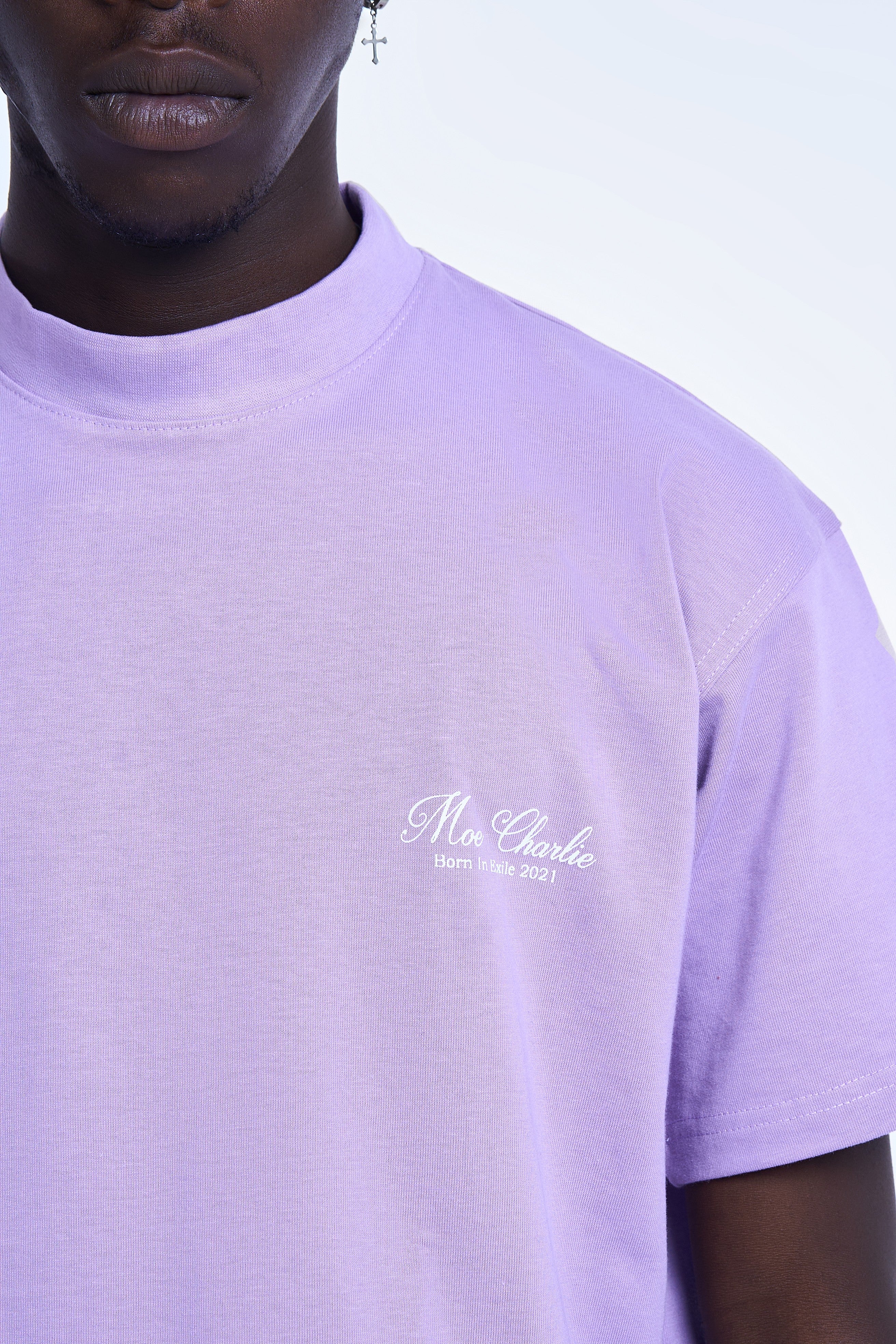 Nahaufnahme Brustlogo MOE CHARLIE Basic T-Shirt Lavendel – Script-Stickerei Moe Charlie Born In Exile 2021 in Weiß
