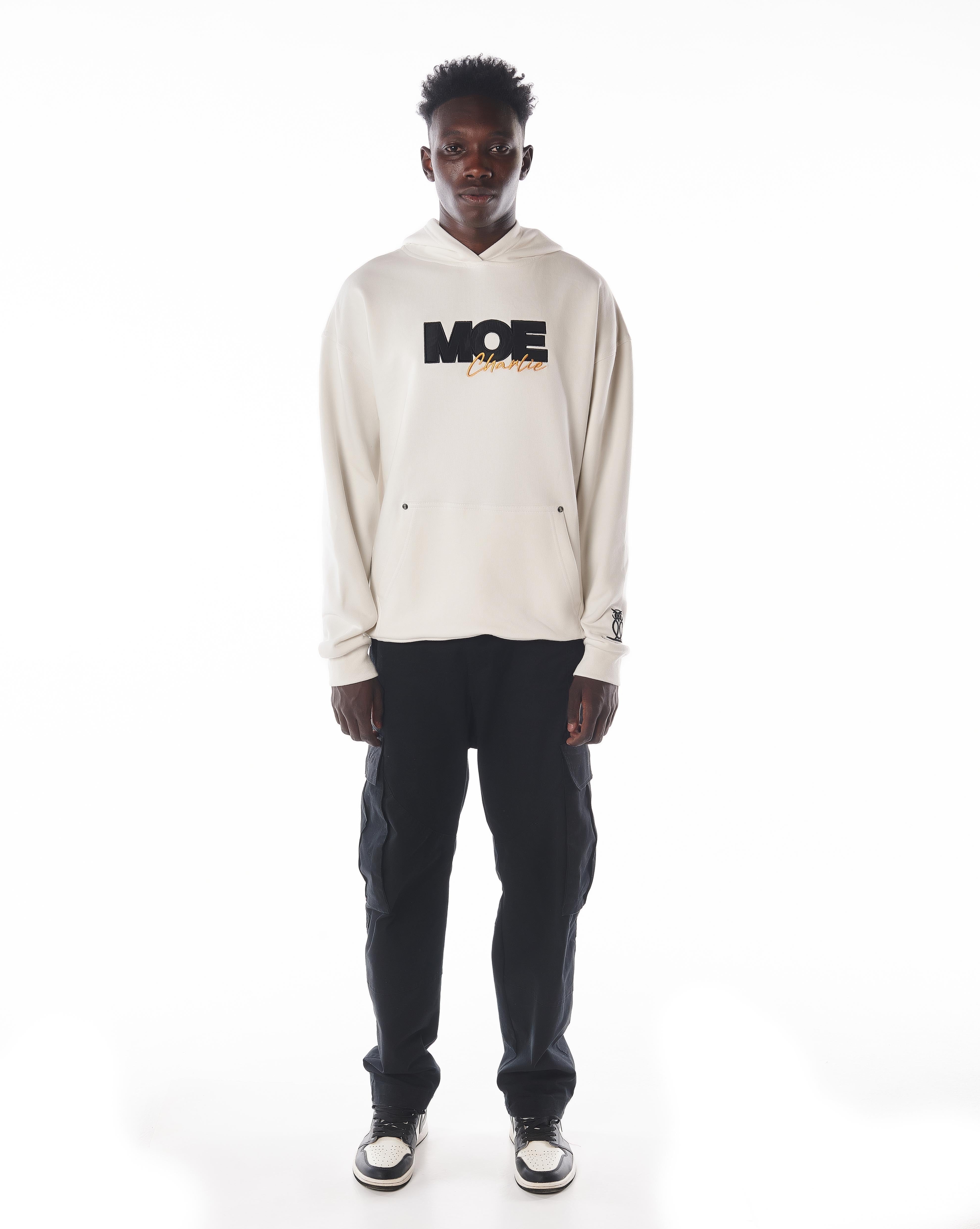 Frontansicht MOE CHARLIE Gold Passion Hoodie in Creme, schwarze MOE-Stickerei mit goldenem Charlie-Schriftzug