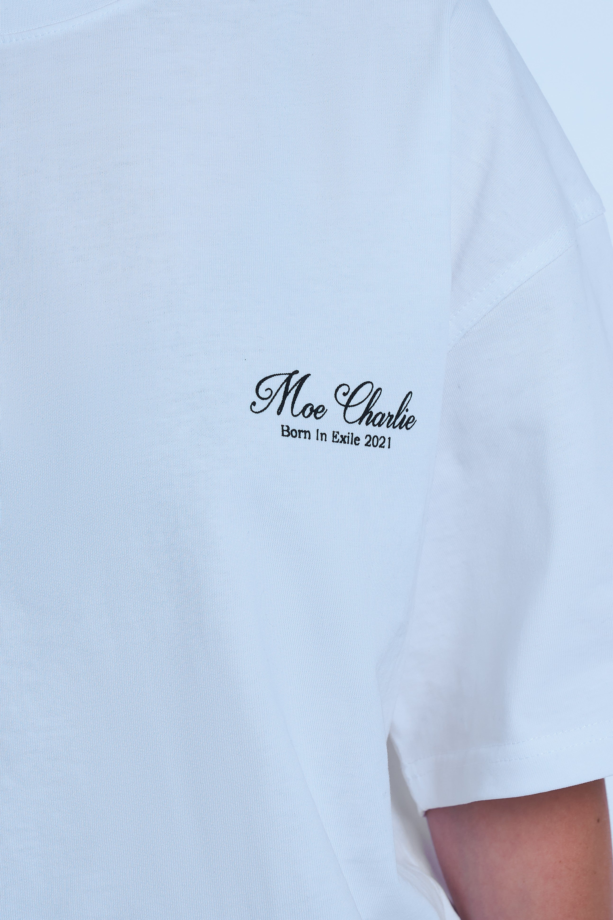 Detailaufnahme Brustlogo MOE CHARLIE Ready To Die Weiß – schwarze Kursivschrift Born In Exile 2021 auf Weiß