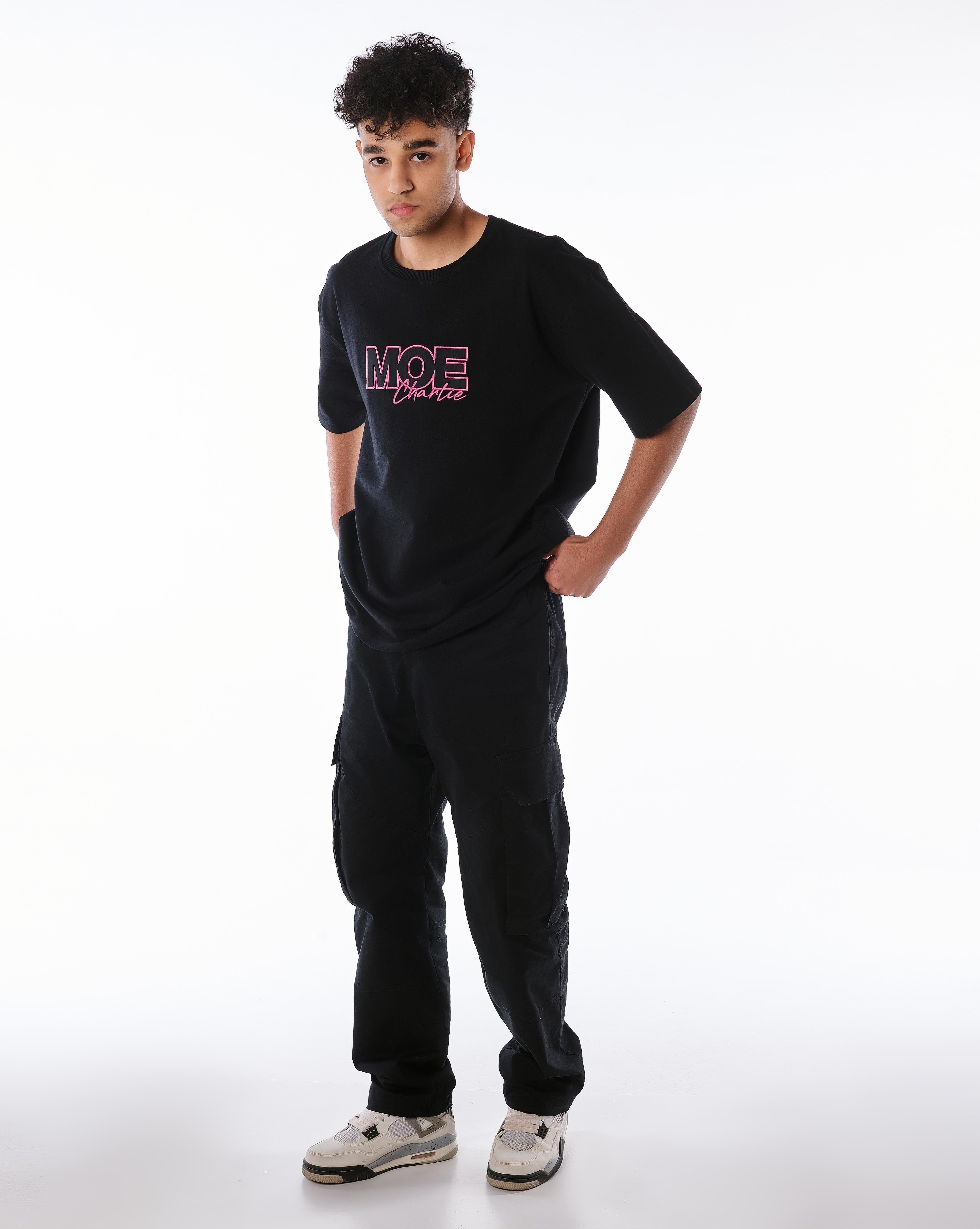 Ganzkörper-Frontansicht MOE CHARLIE Pink Passion T-Shirt, pinke Stickerei, Hand auf Hüfte, lässige Pose