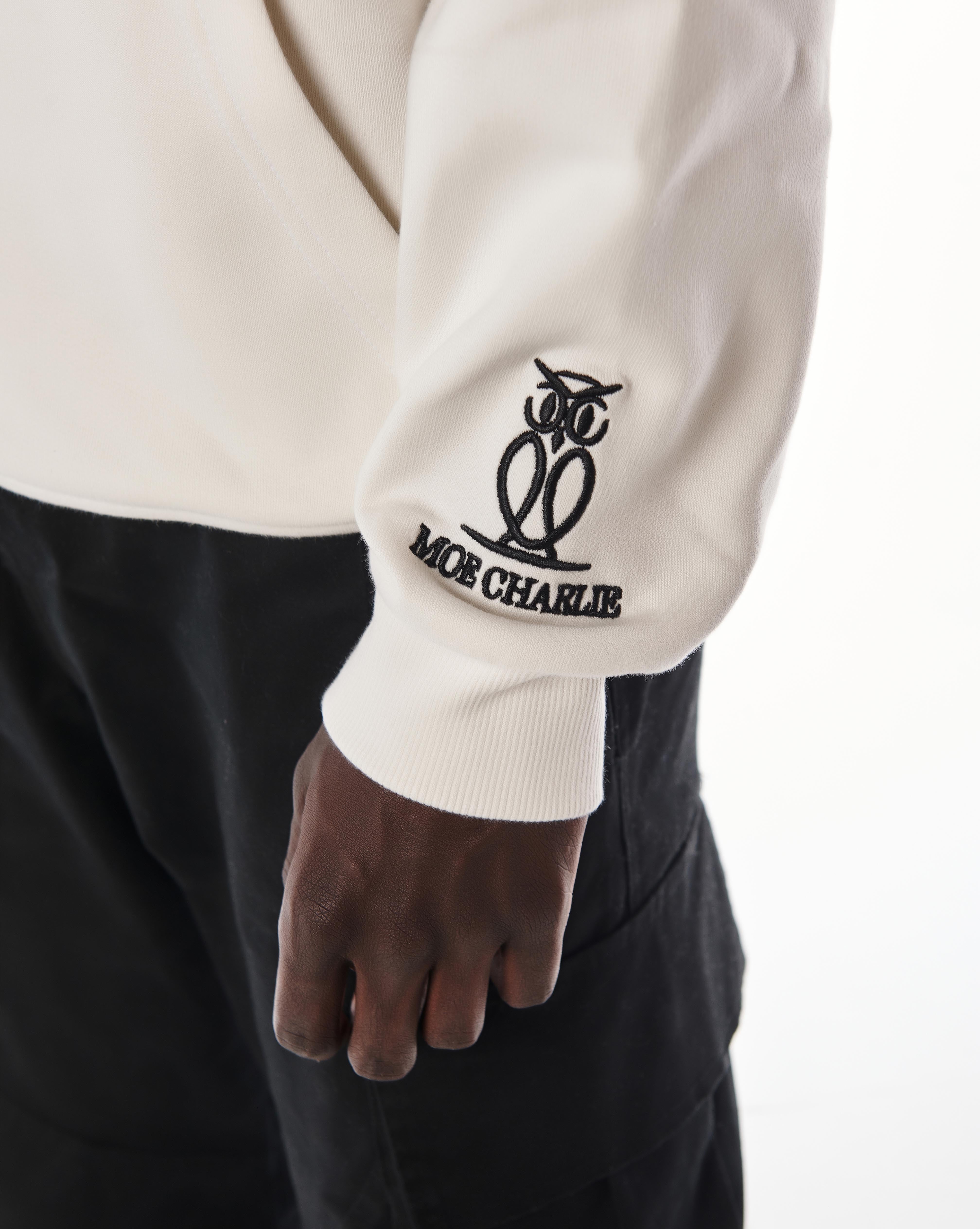 Detailaufnahme Ärmelstickerei MOE CHARLIE Gold Passion Hoodie, schwarzes Eulen-Logo am Bündchen, Nahaufnahme