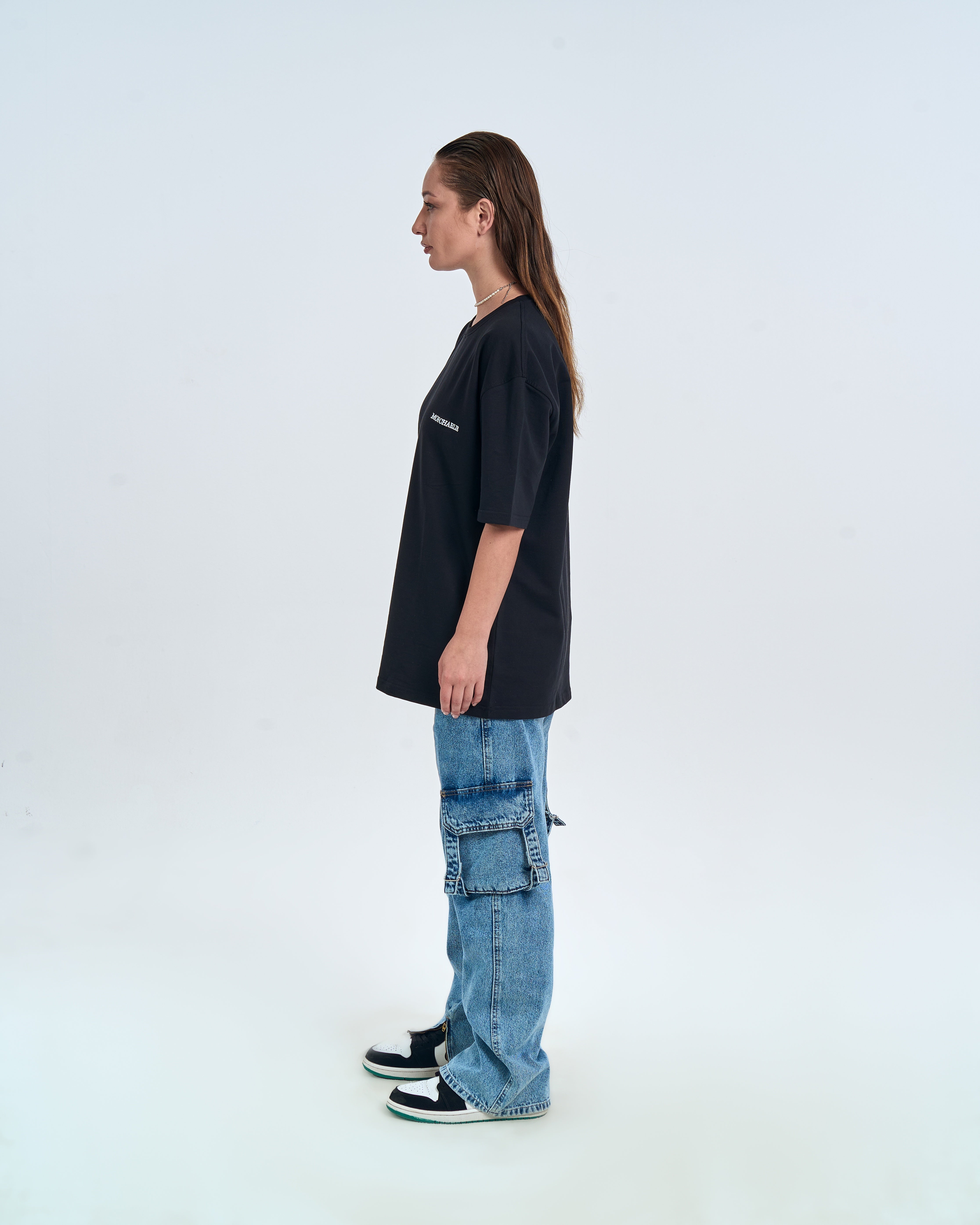 MOE CHARLIE Basic T-Shirt Schwarz – Seitenansicht Damenmodel, Oversize-Länge, hellblaue Cargo-Jeans, Air Jordan