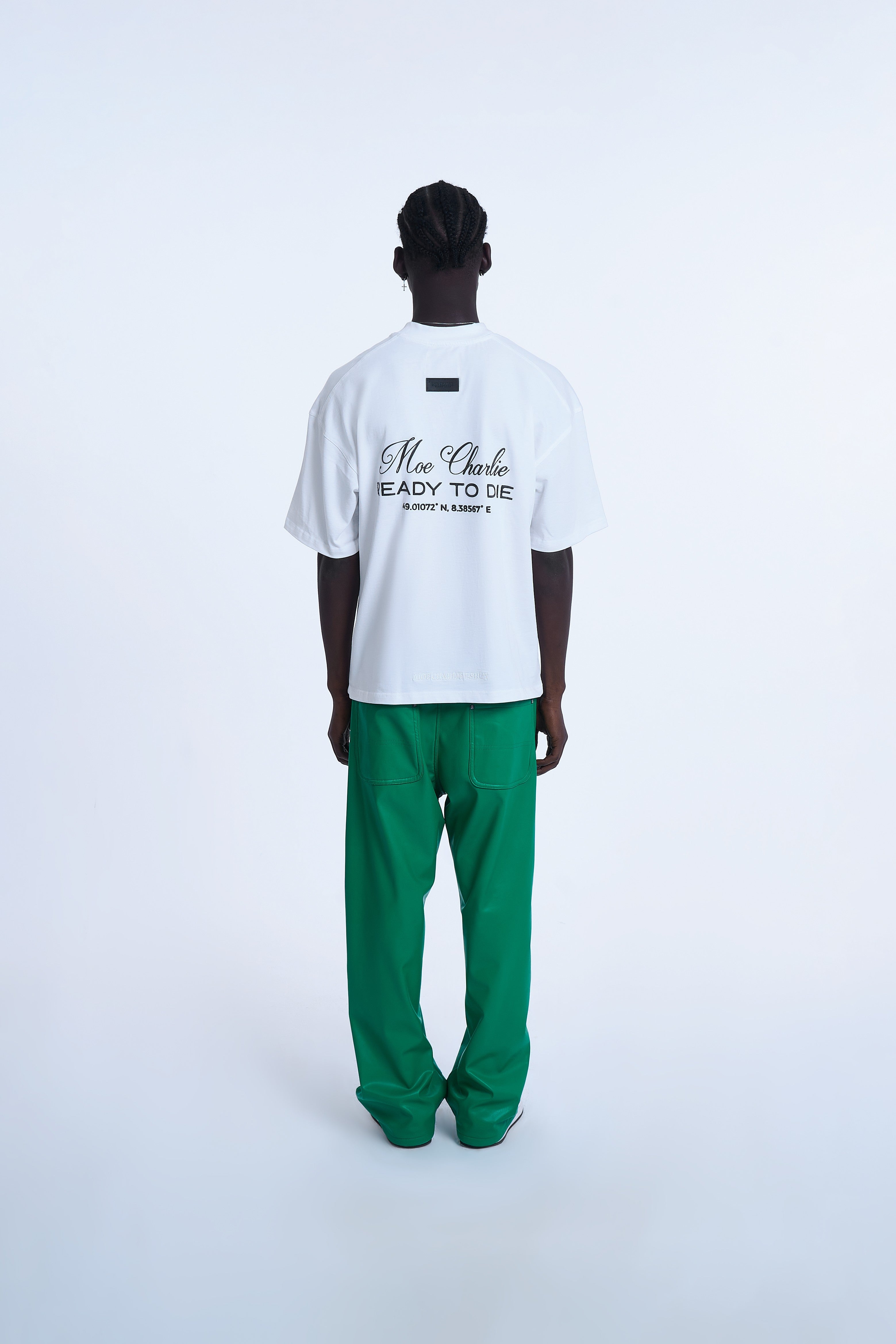 Rückenansicht MOE CHARLIE Ready To Die T-Shirt Weiß – schwarzer Script-Blockprint mit Koordinaten, grüne Pants