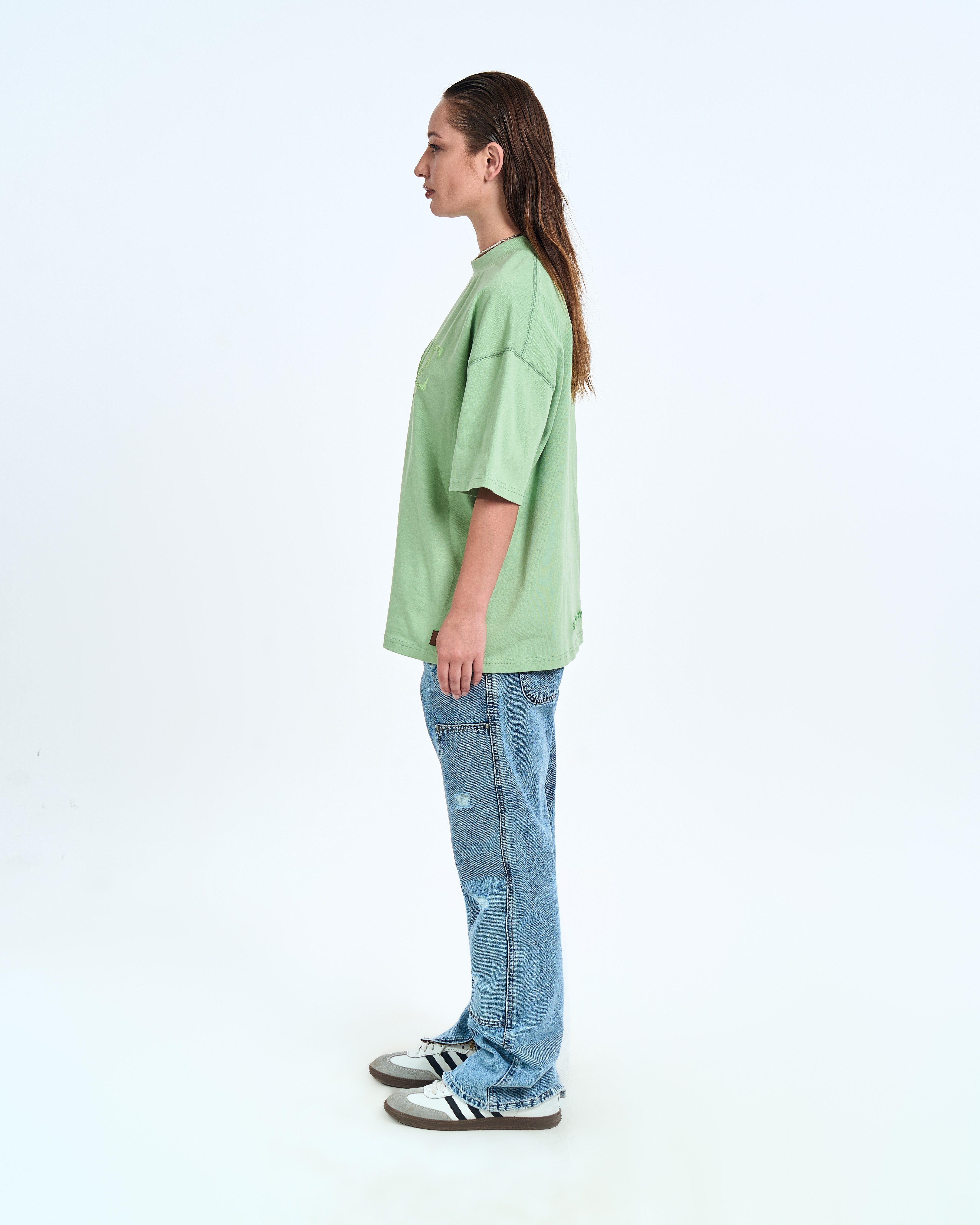Seitenansicht weiblicher Model MOE CHARLIE Mintgrün Basic Tee – linkes Profil, Adidas Samba, Distressed Jeans