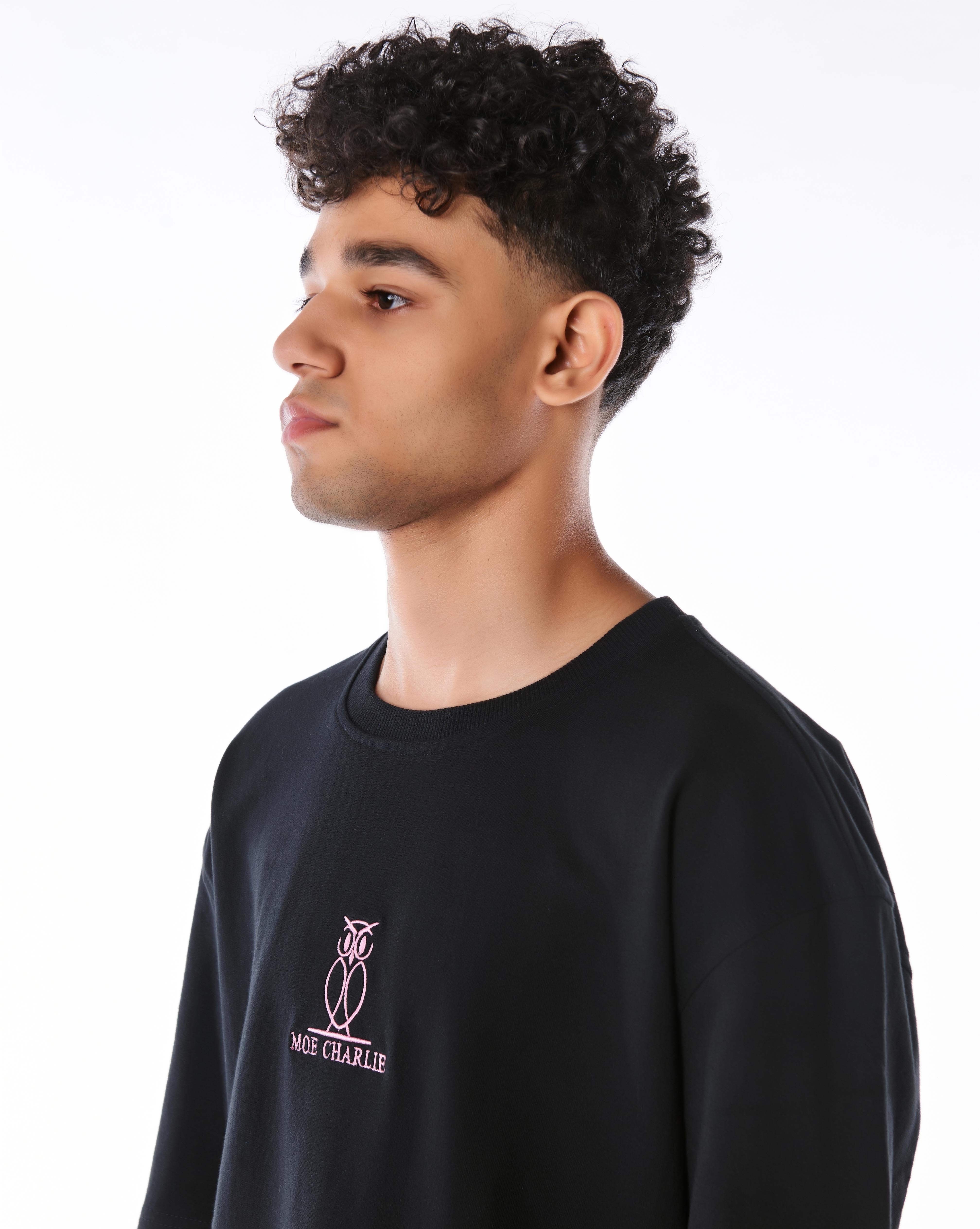Seitliches Hochformat des MOE CHARLIE Pink Logo T-Shirts, Fokus auf rosa Brust-Stickerei und cleanem Ärmeldesign