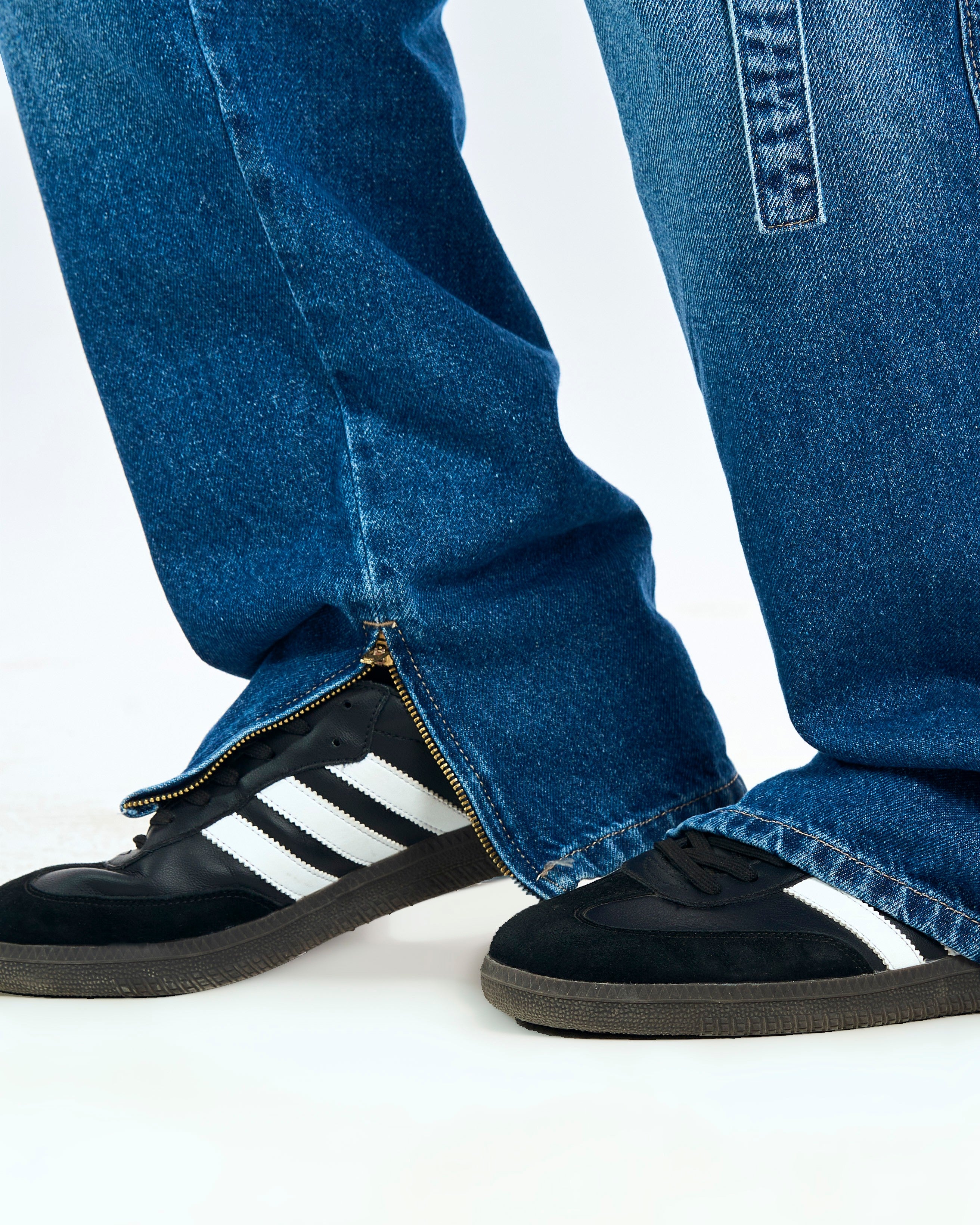Saum-Detail der MOE CHARLIE Cargo Denim – Knöchel-Zipper geöffnet, kombiniert mit schwarzen Adidas Samba Sneakers