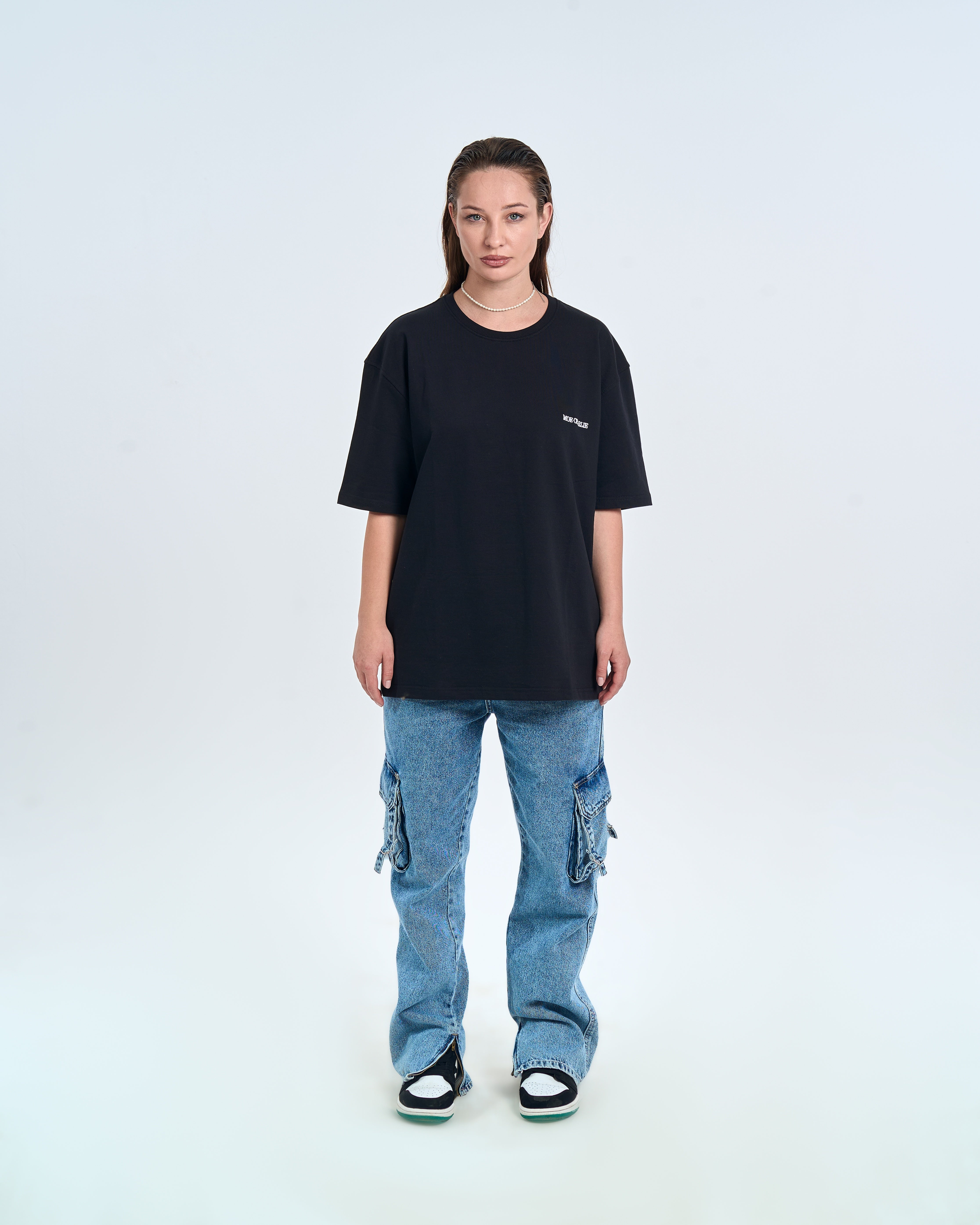 MOE CHARLIE Basic T-Shirt Schwarz – Frontansicht Damenmodel, Perlenkette, Cargo-Jeans und Air Jordan Sneaker