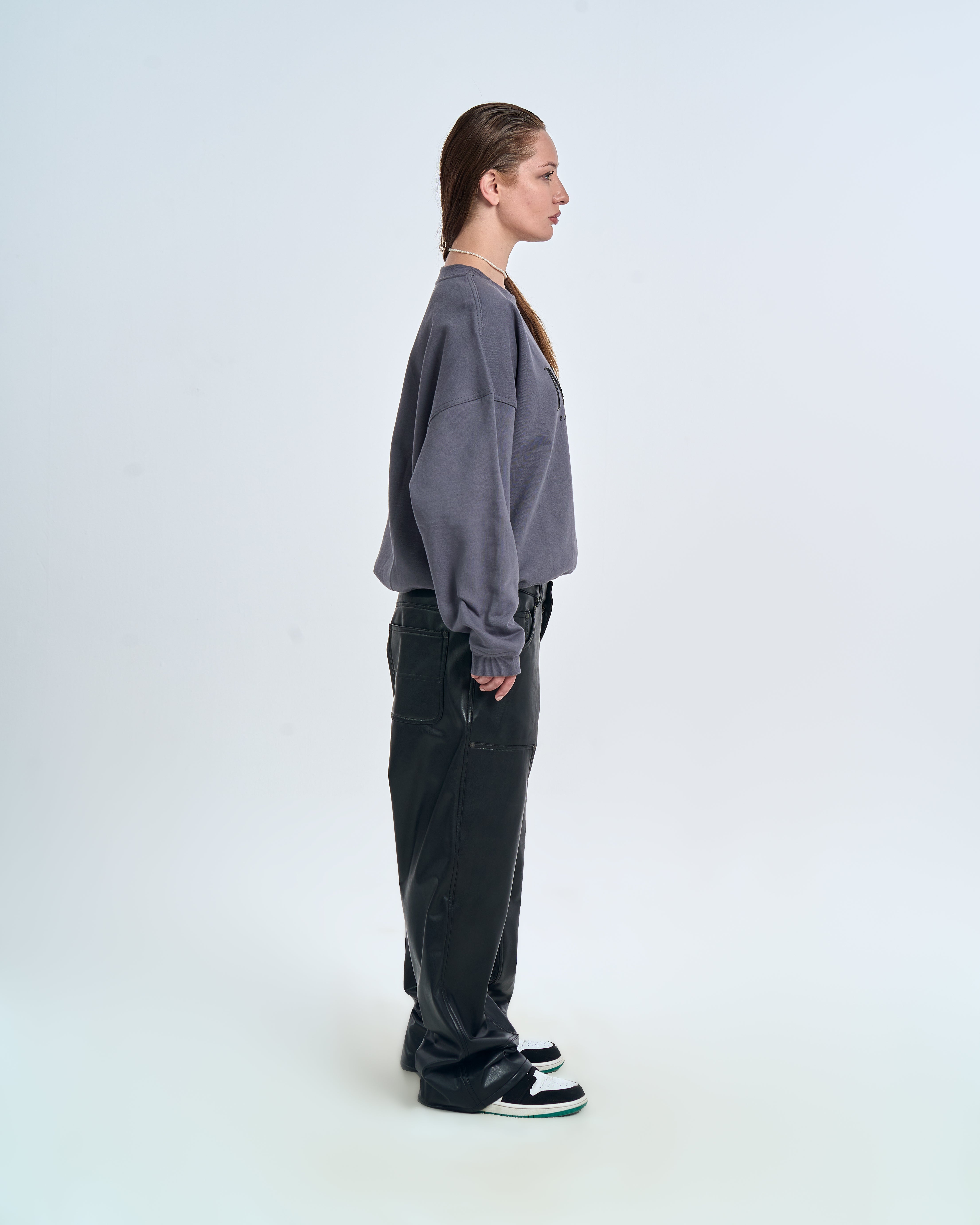 Born in Exile Sweatshirt Grau MOE CHARLIE, rechte Seitenansicht weiblich, schwarze Lederhose und Sneakers