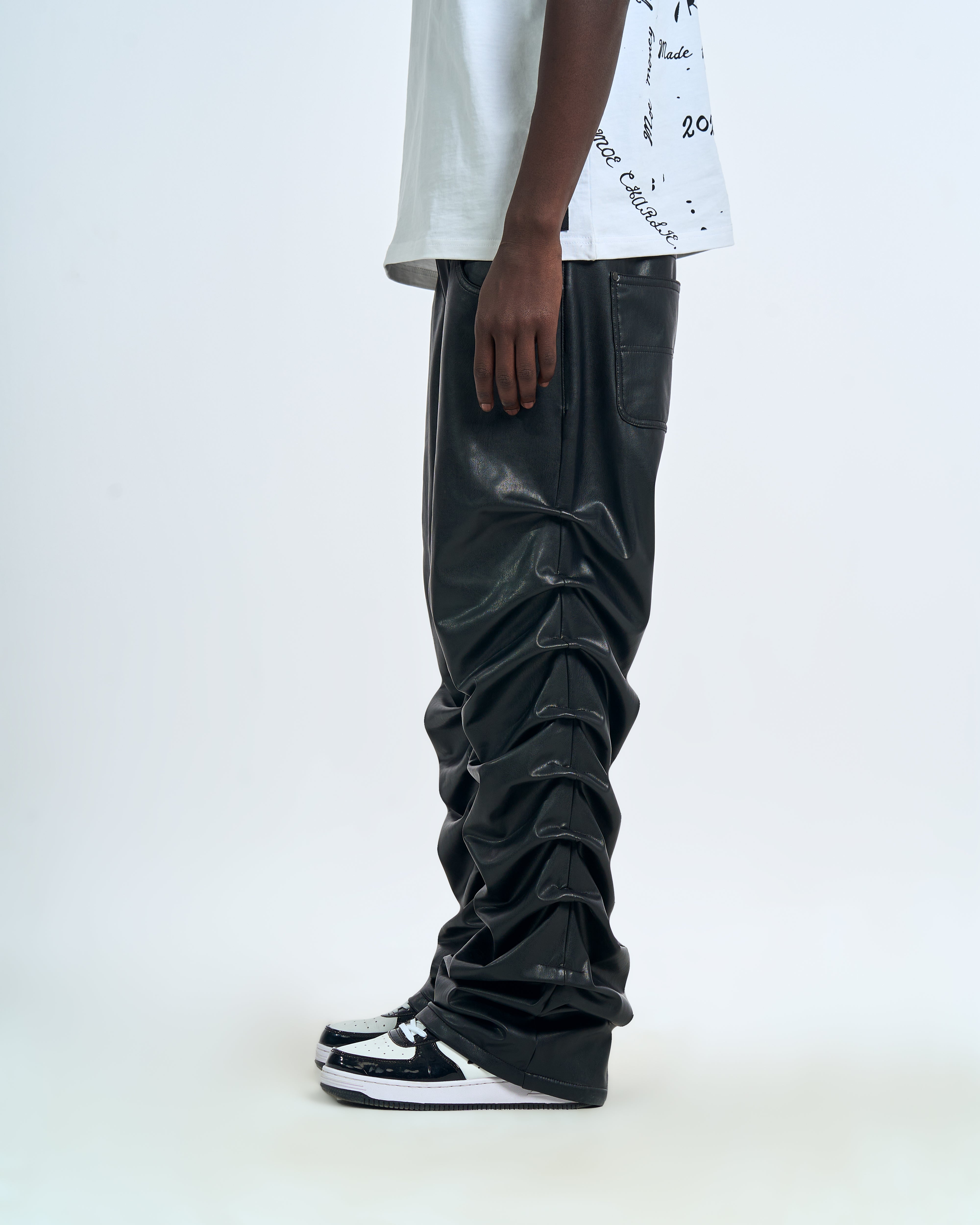 Crow Leather Pants MOE CHARLIE Schwarz, linke Seitenansicht maennlich, extremes Leather-Stacking und Sneakers