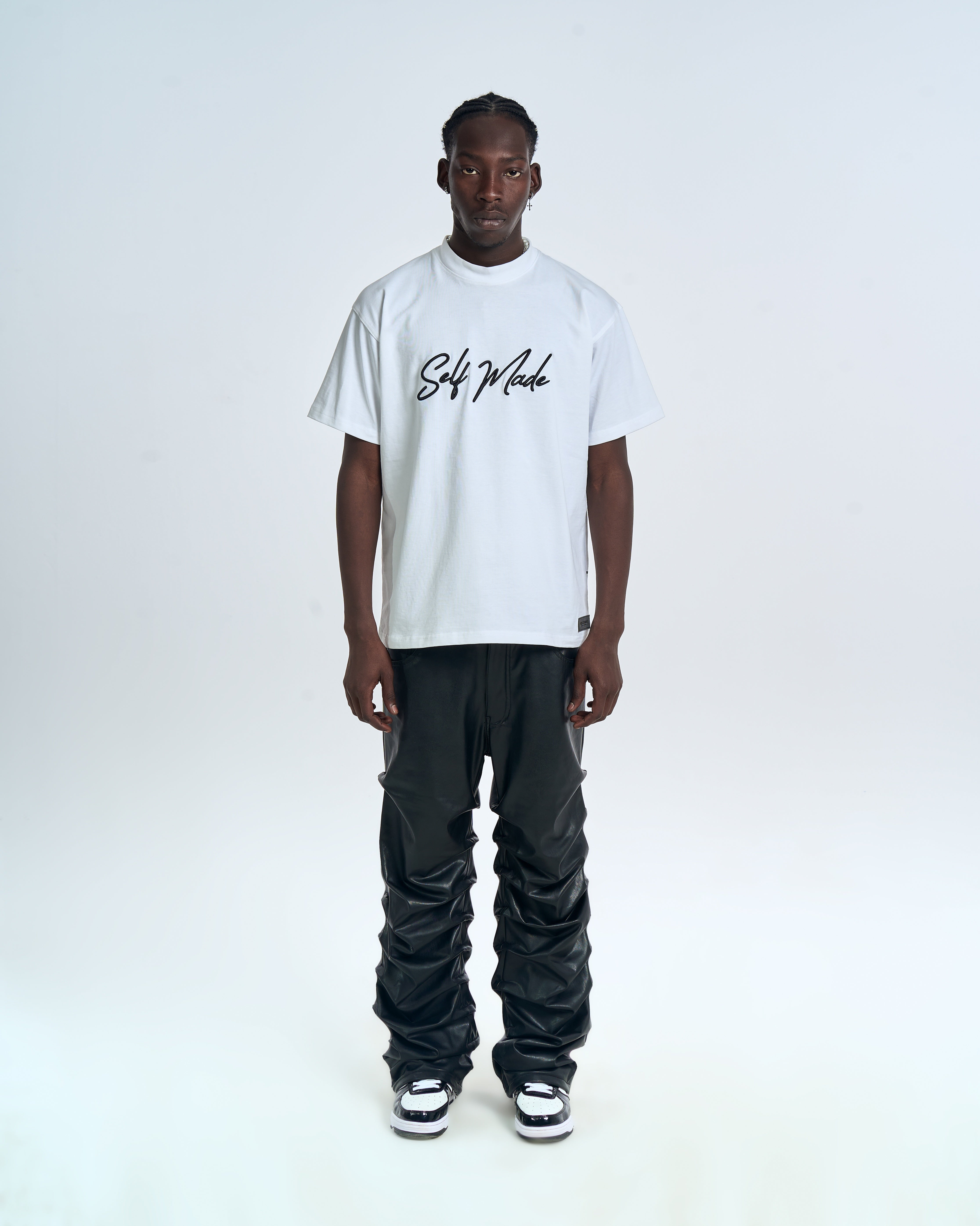 MOE CHARLIE Self Made T-Shirt front – weißes Oversize-Tee, schwarzer Brush-Script auf Brust, schwarze Lederhose