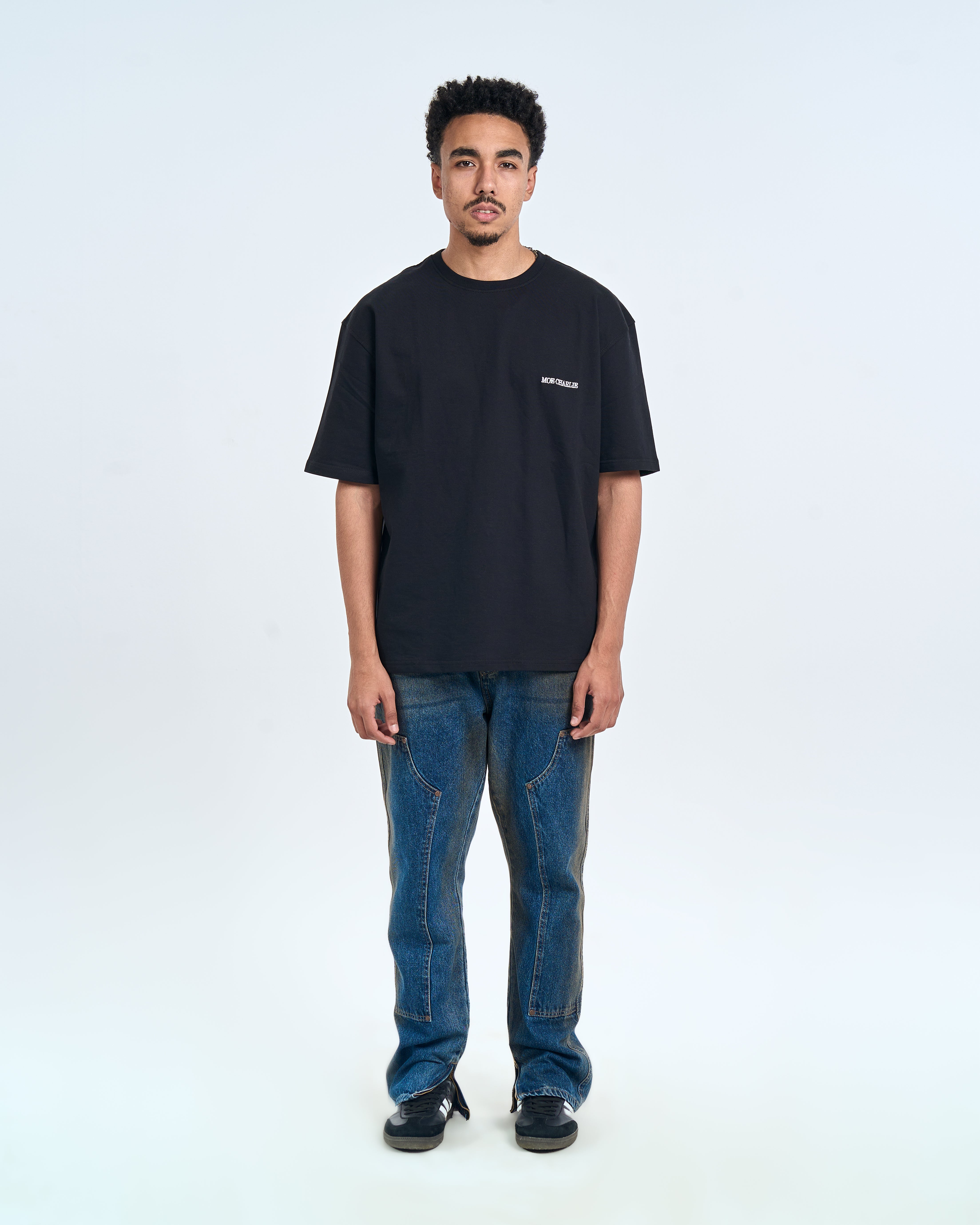 MOE CHARLIE Basic T-Shirt Schwarz – Frontansicht Herrenmodel, Oversize kombiniert mit blauen Carpenter-Jeans